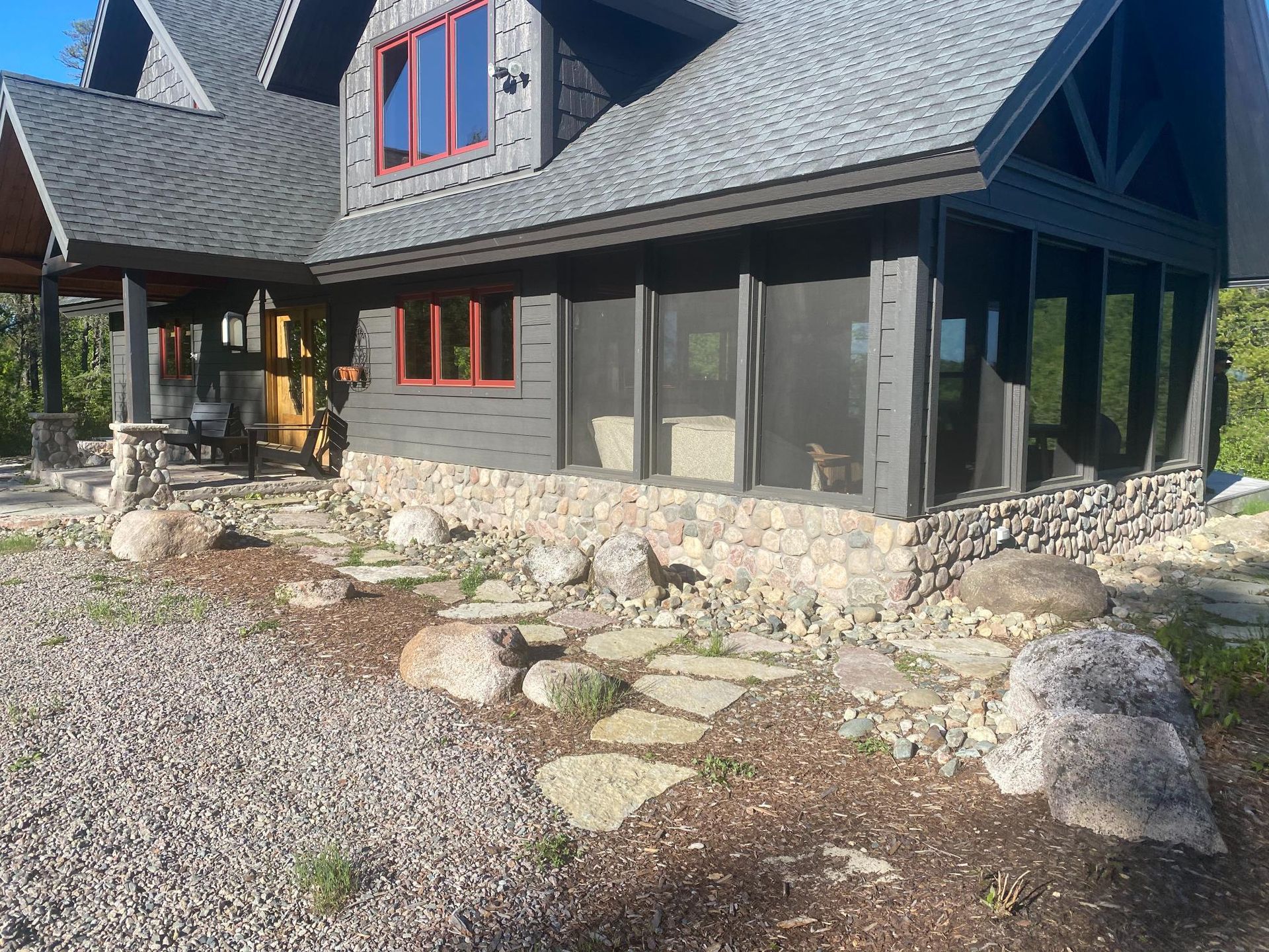 A large house with a screened in porch and a stone wall