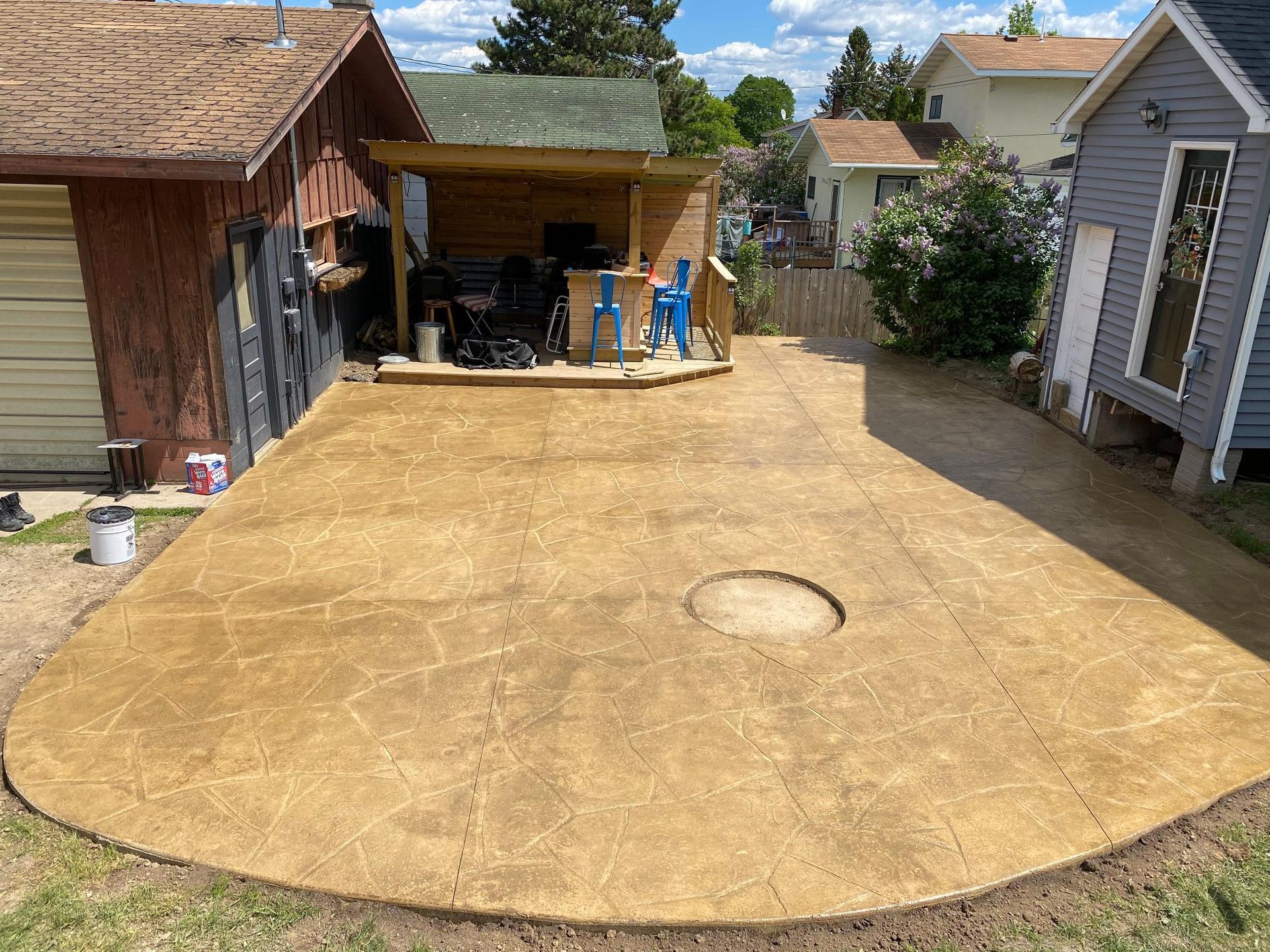 A driveway with a hole in the middle of it and a house in the background.