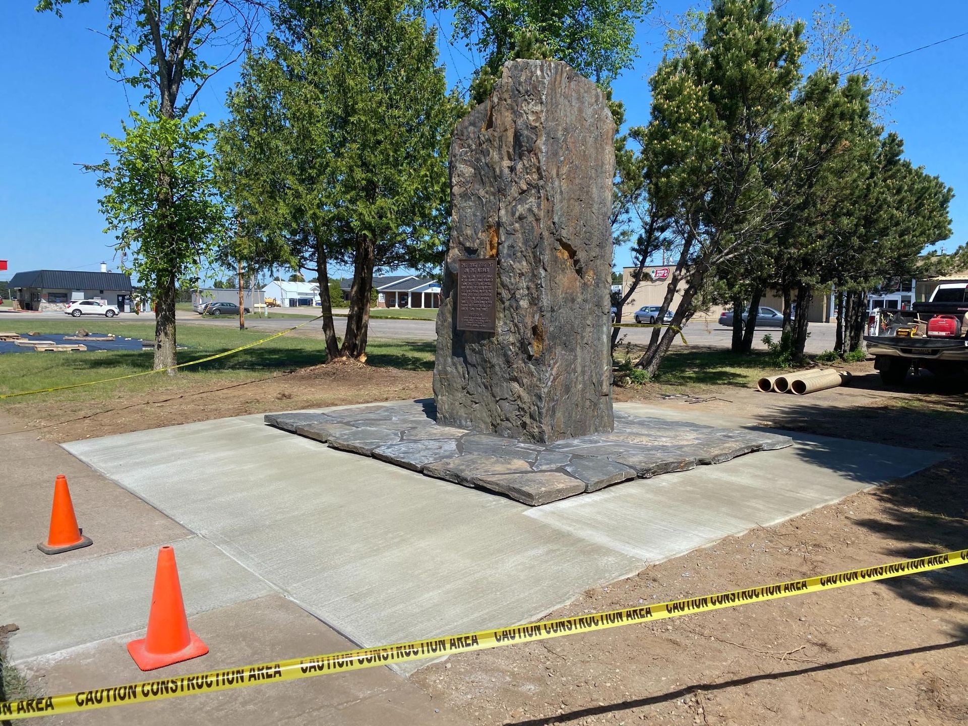 A large stone statue is surrounded by orange cones and yellow tape.