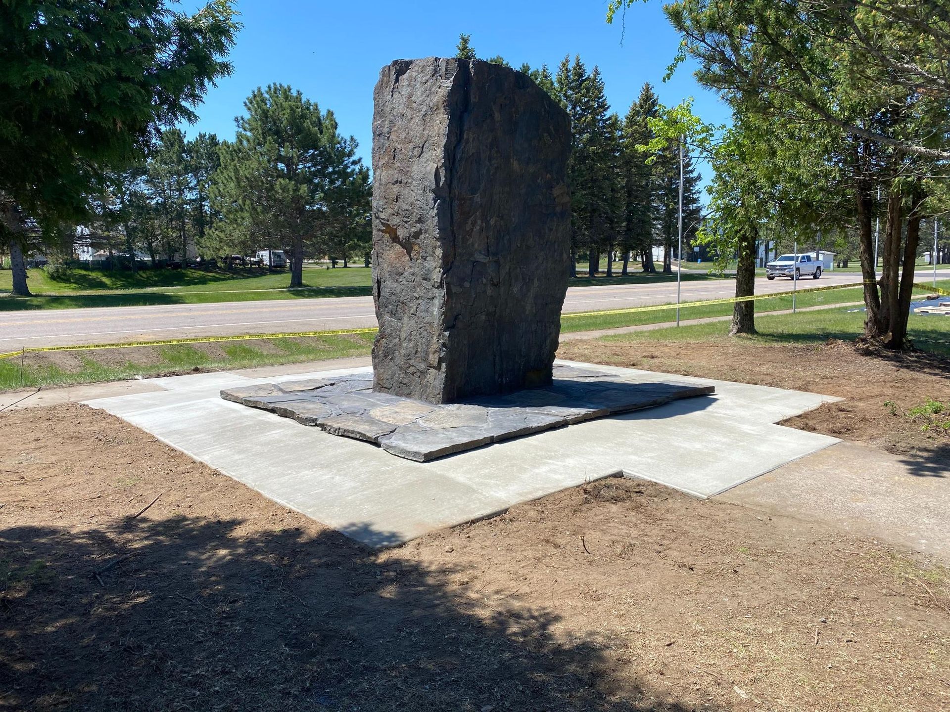 A large rock is sitting in the middle of a park.