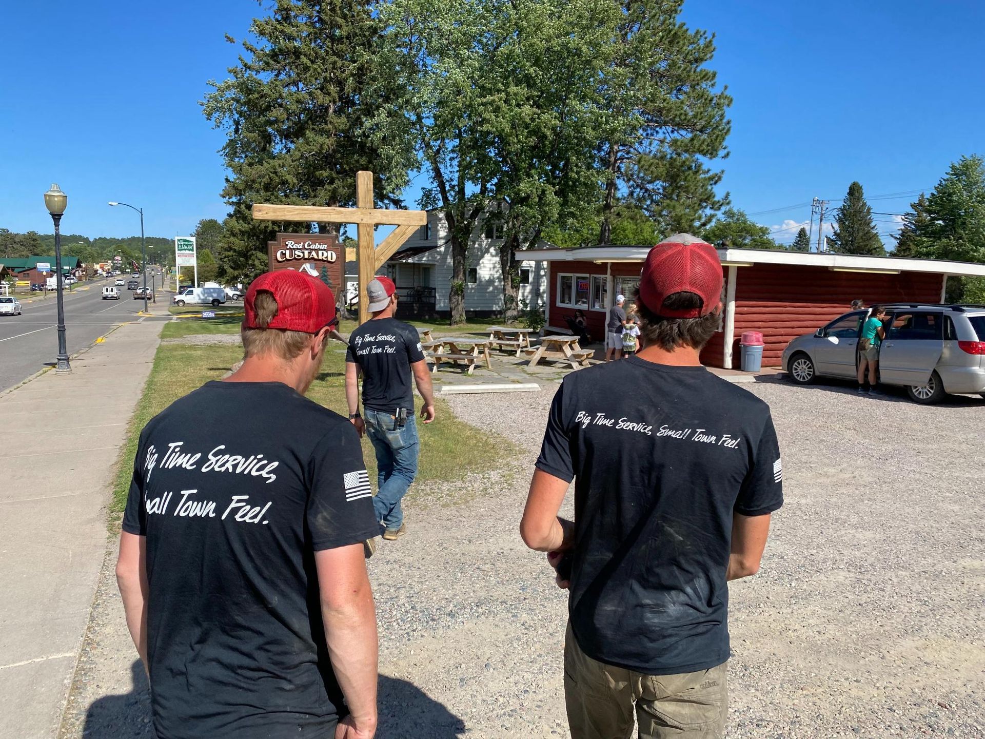 Two men wearing black t-shirts are walking down a sidewalk.