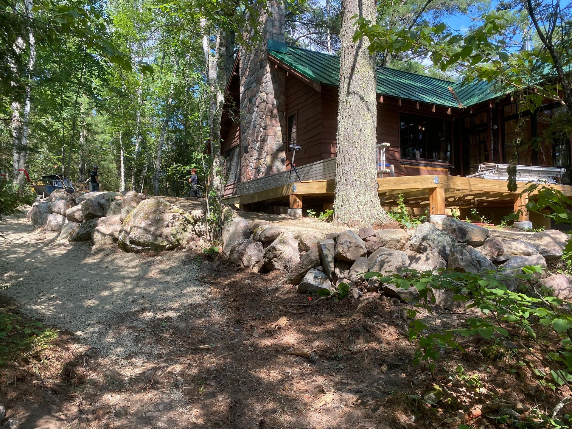 A house is surrounded by trees and rocks in the middle of a forest.