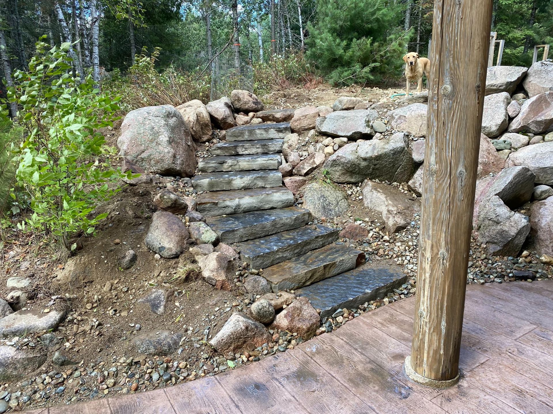 A set of stone stairs leading up to a wooden post in a rocky area.