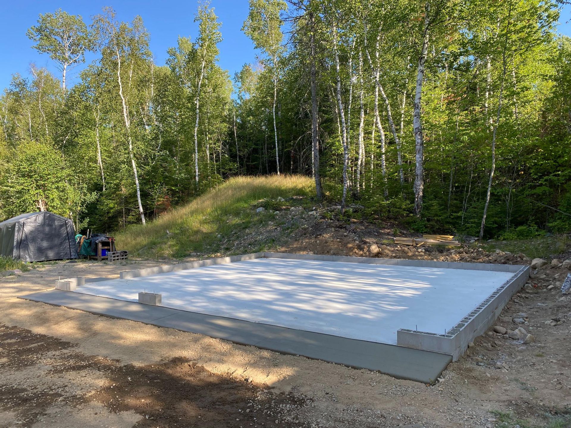 A concrete base is being built in the middle of a forest.