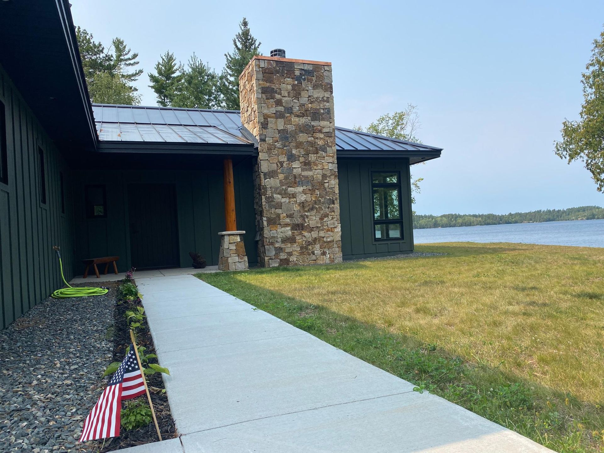 A house with a stone chimney and a walkway leading to it.