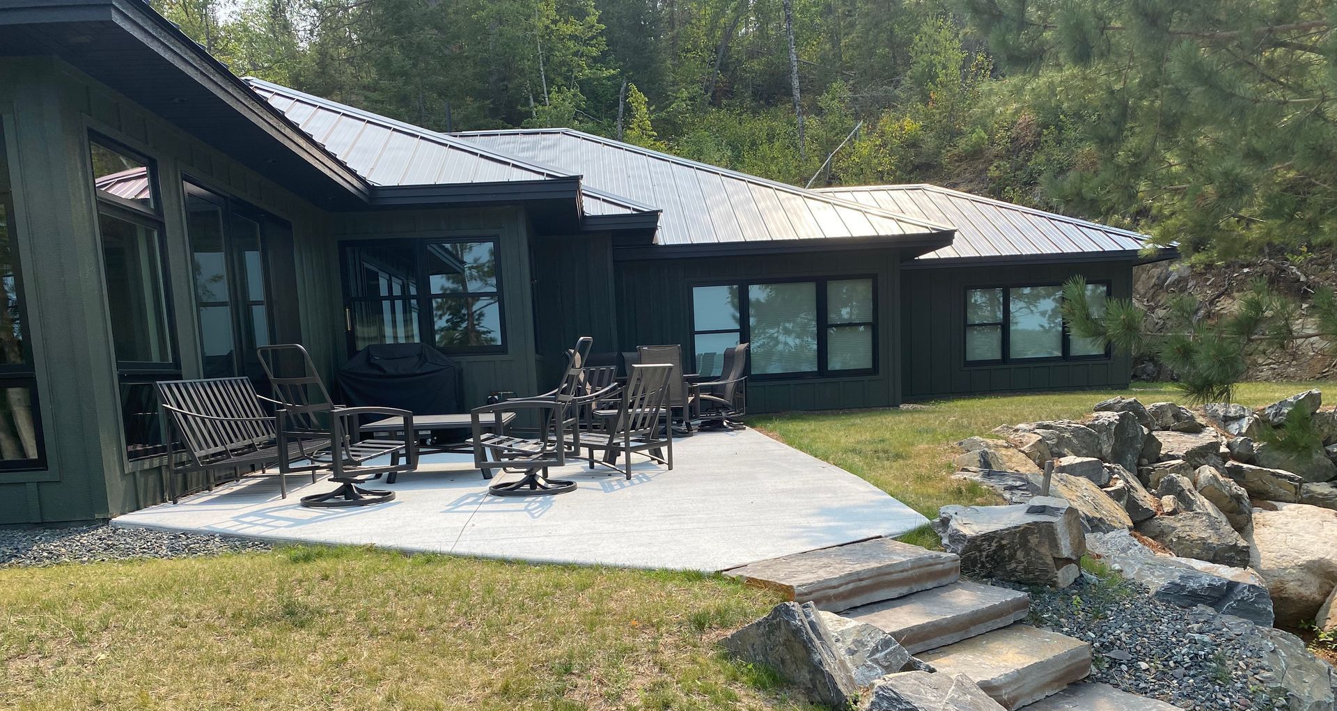 A large house with a patio and chairs in front of it.
