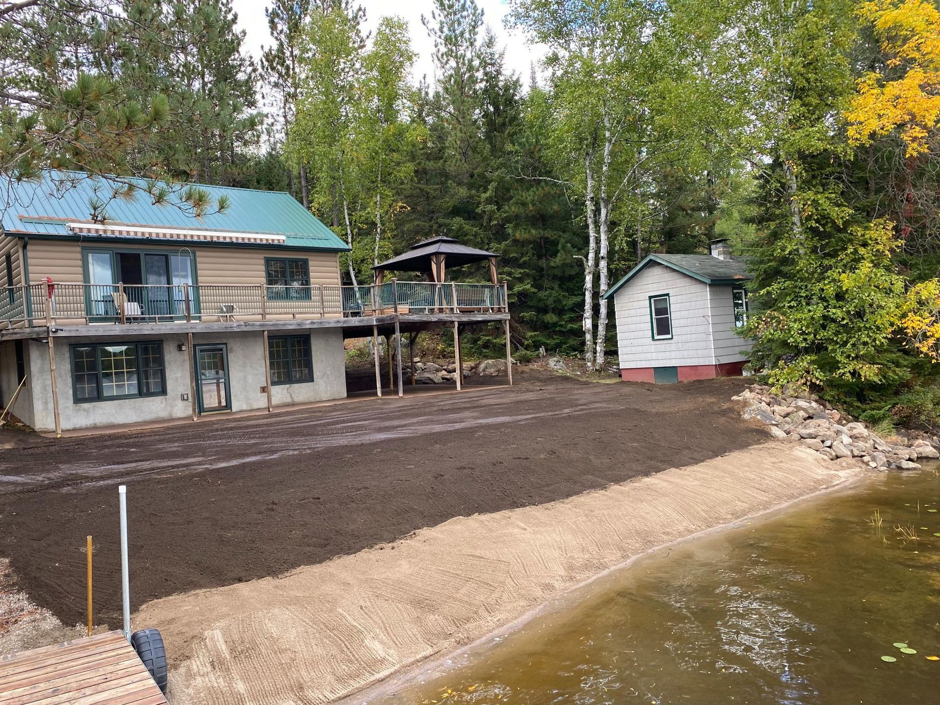 A house with a blue roof is sitting next to a body of water.