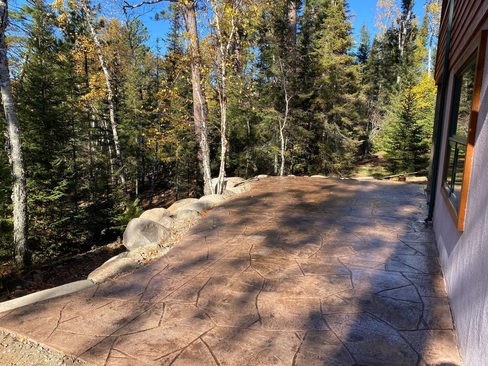 A concrete driveway leading to a house with trees in the background.