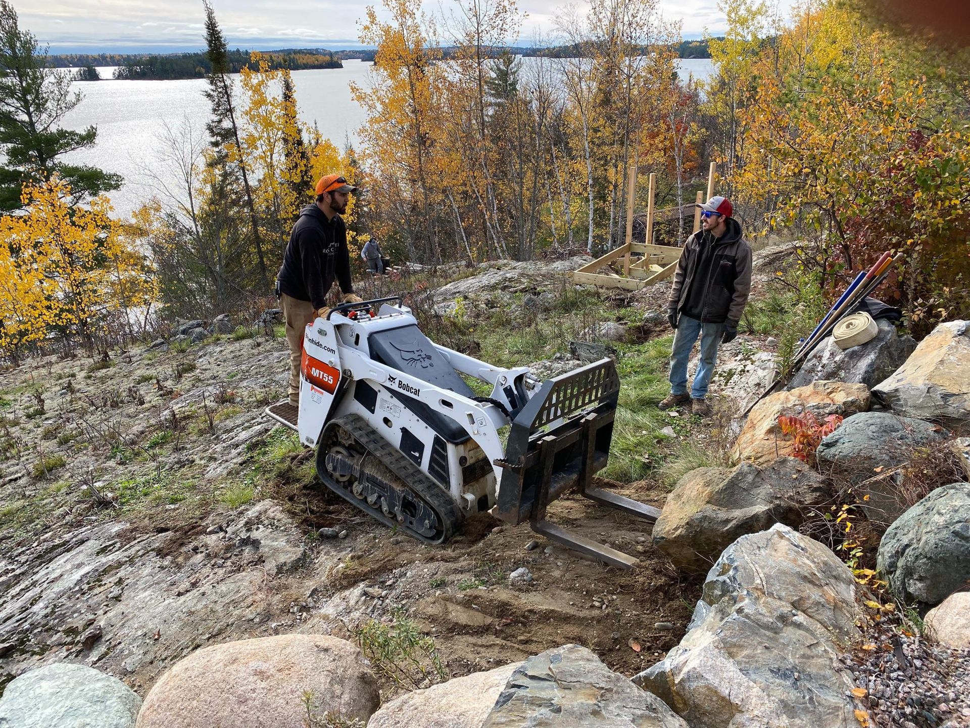 A man is standing next to a bulldozer on a rocky hillside.