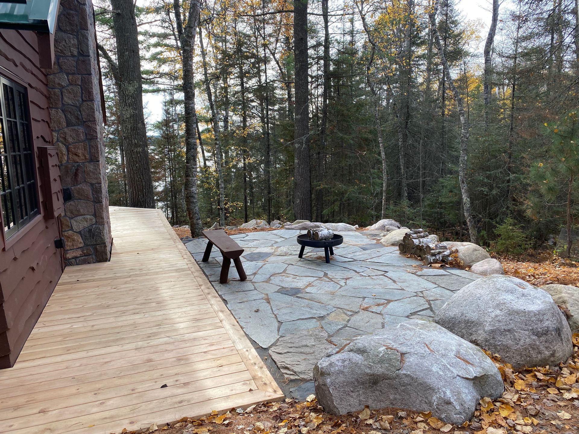 A wooden deck with a fire pit in the middle of the woods