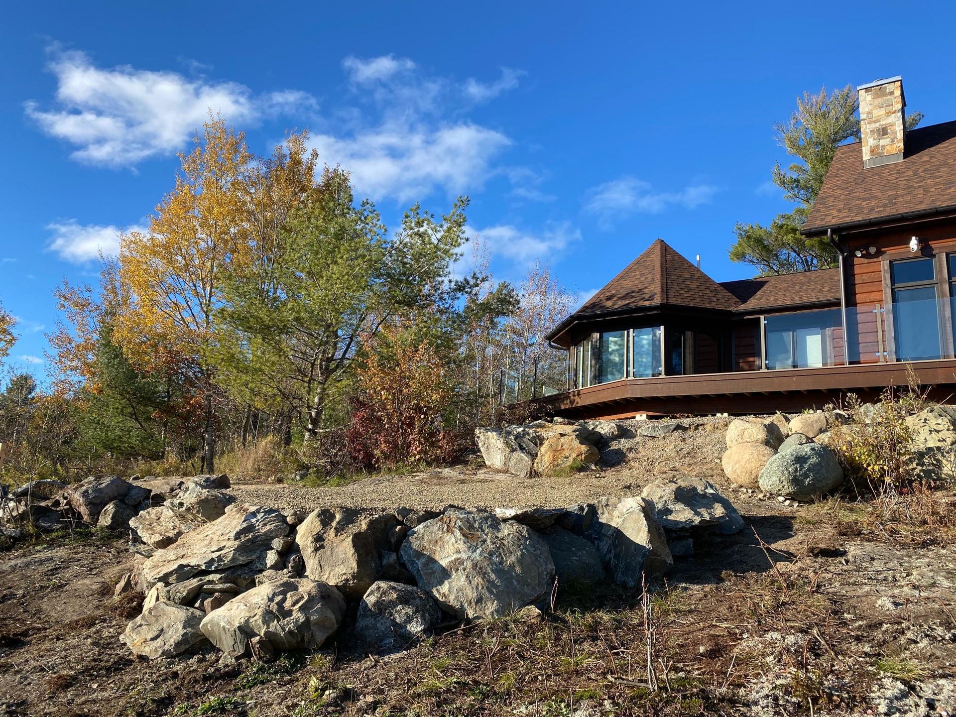 A large house is sitting on top of a rocky hill surrounded by trees.
