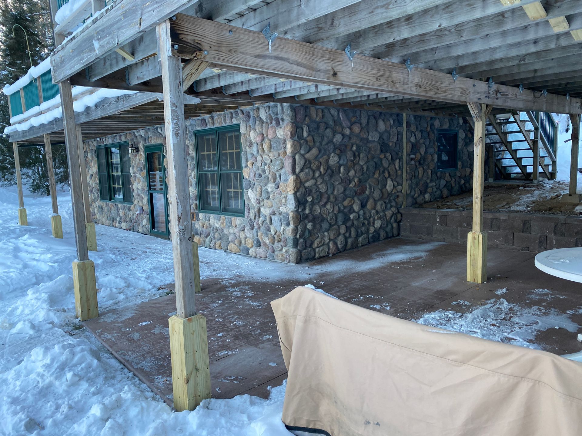 A stone building with a covered patio in the snow.
