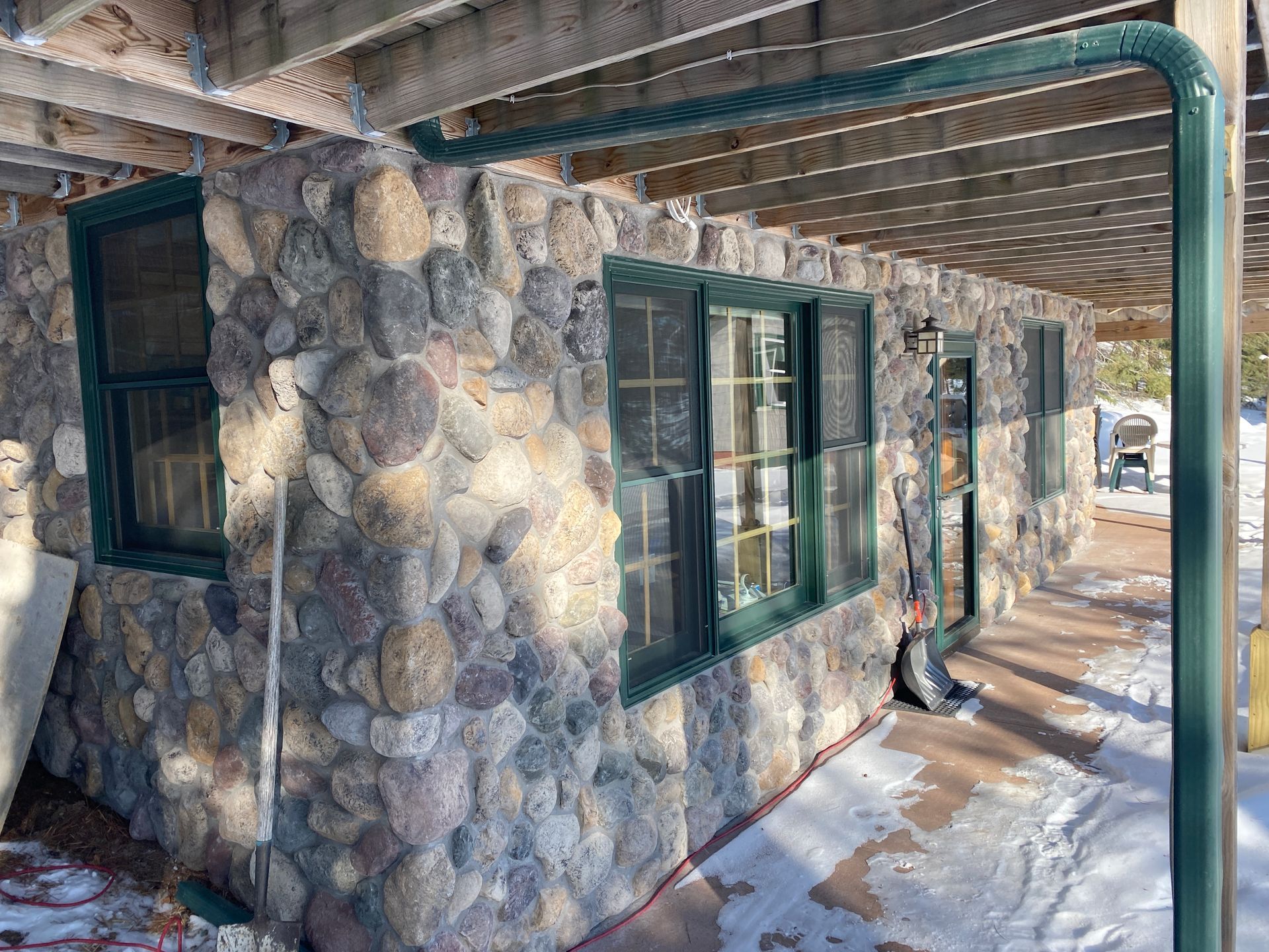 A stone building with green windows and a covered porch.