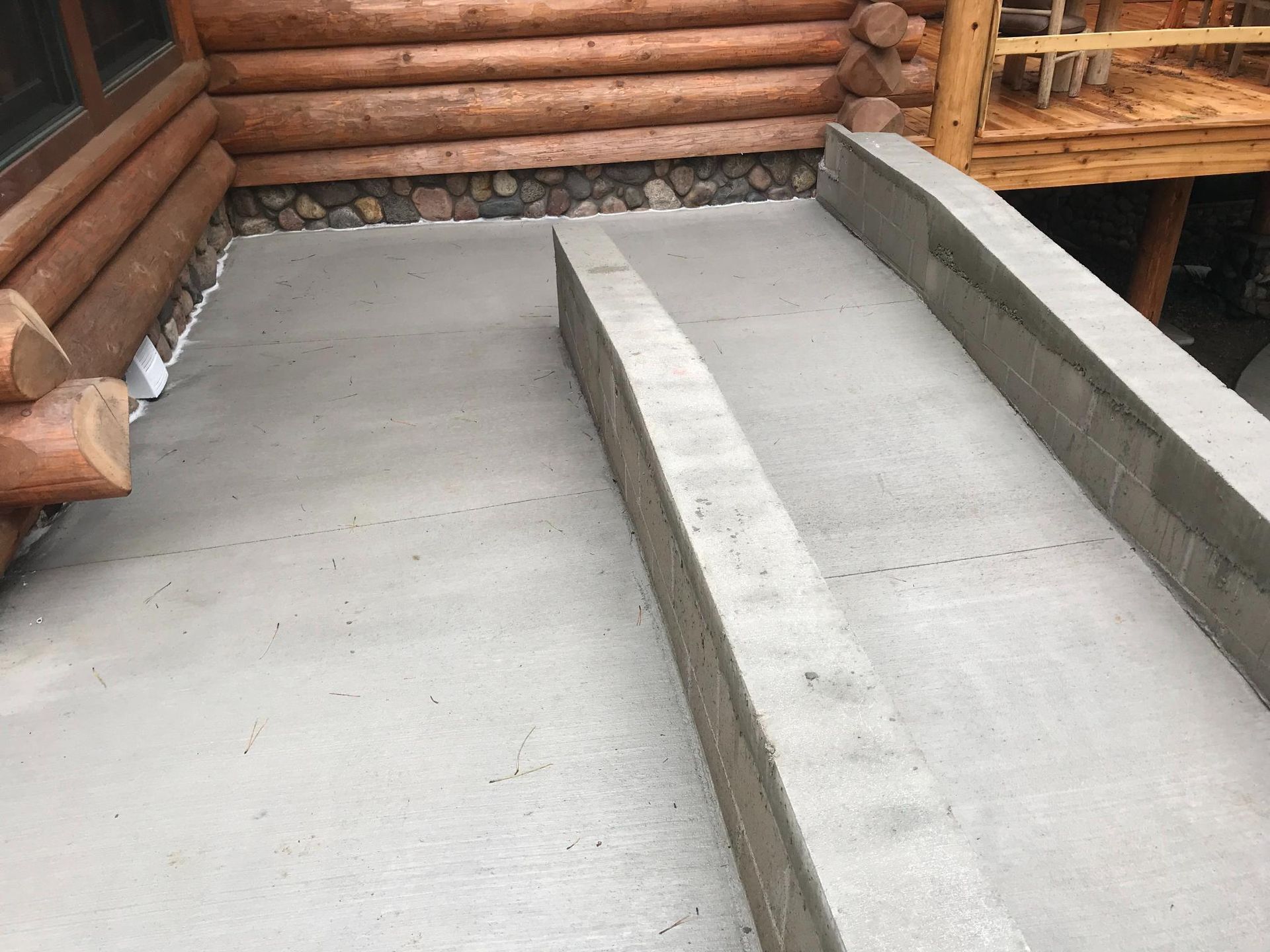 A concrete ramp is being built in front of a log cabin.