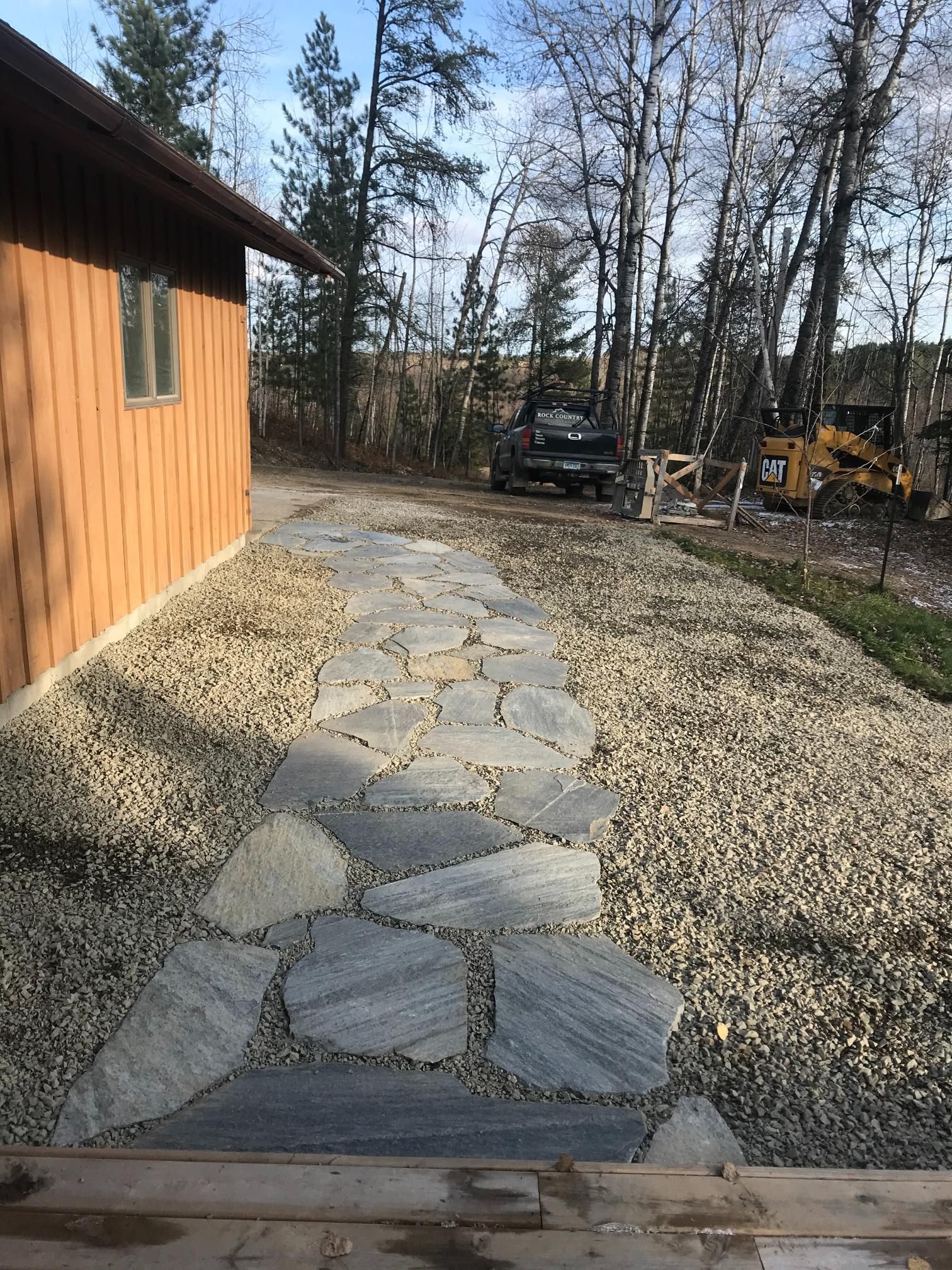A stone walkway leading to a house in the woods.