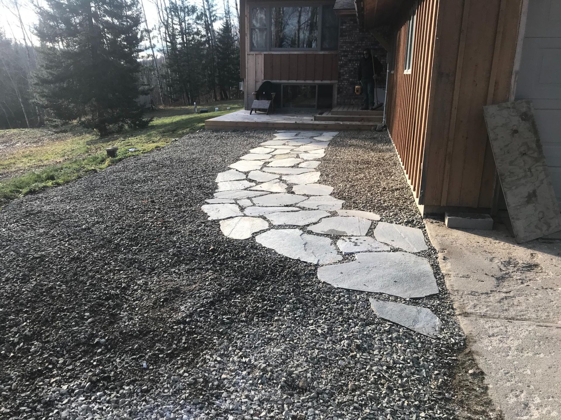 A stone walkway leading to a house on a gravel road.
