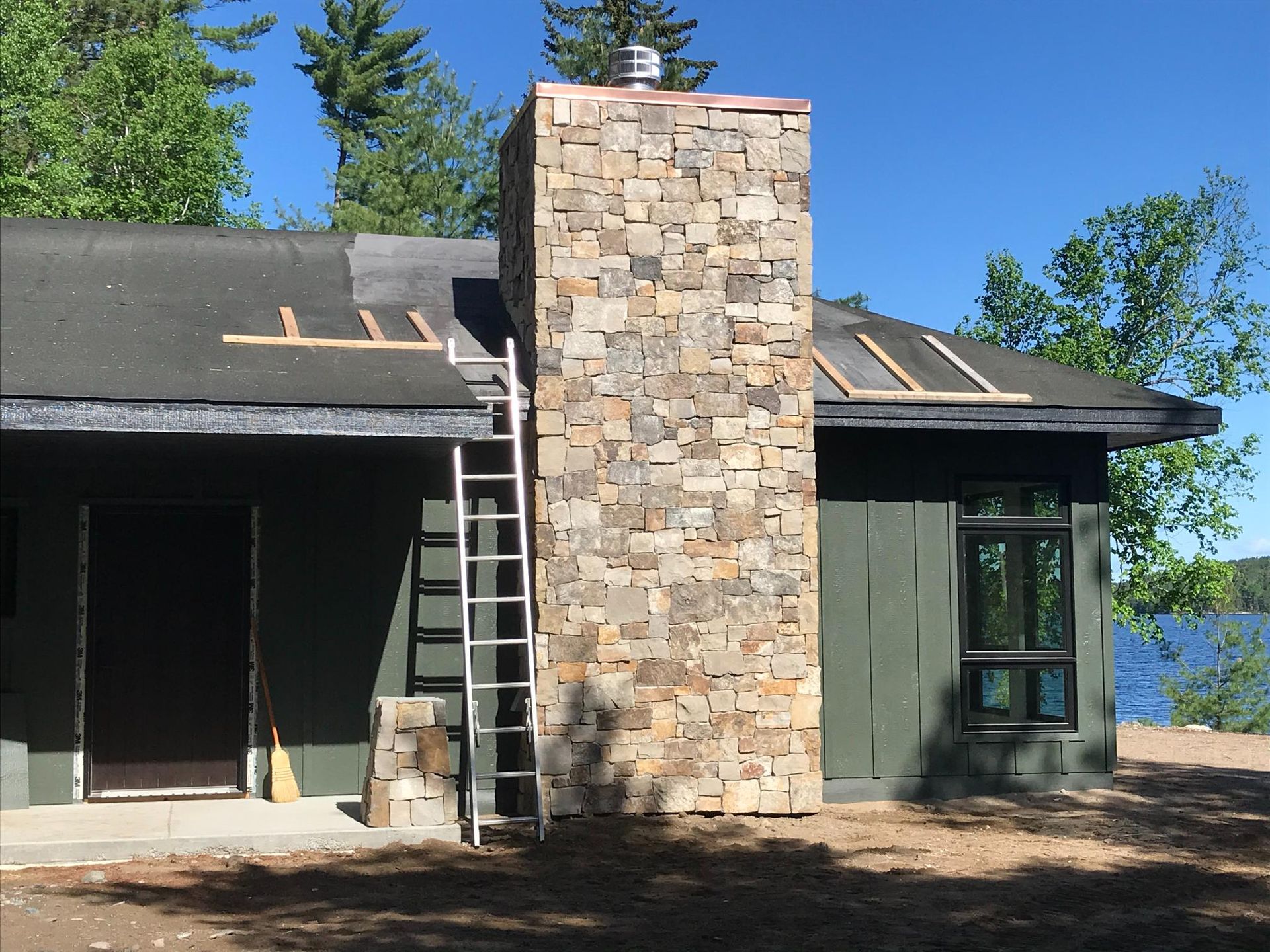 A house with a stone chimney and a ladder in front of it
