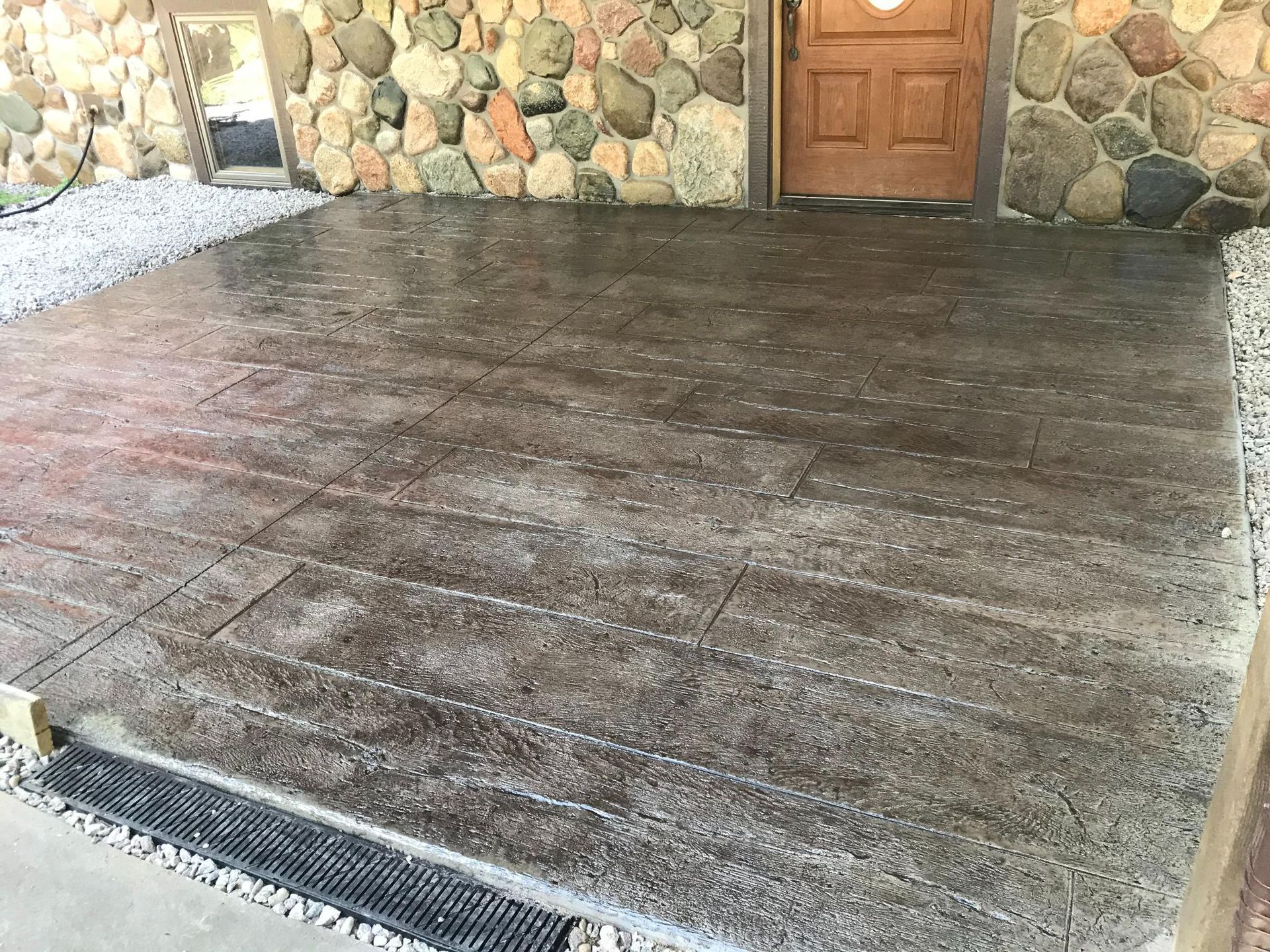 A concrete driveway in front of a stone wall with a wooden door.