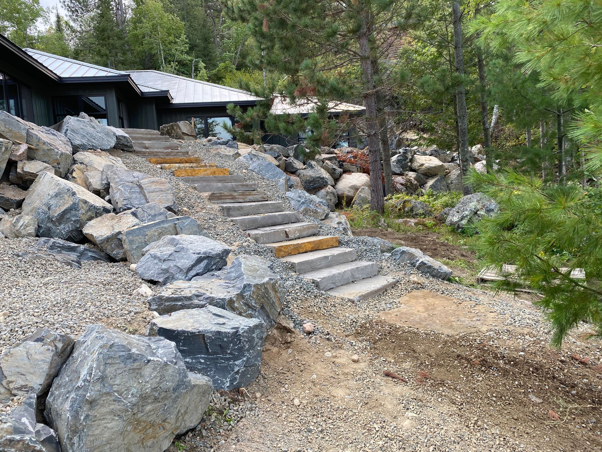 A set of stairs leading up to a house surrounded by rocks and gravel.