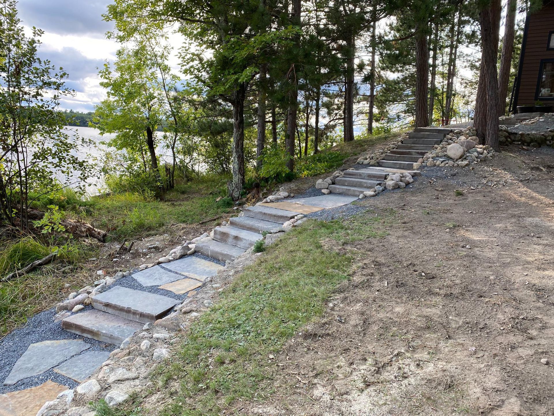 A stone walkway leading to a lake surrounded by trees.