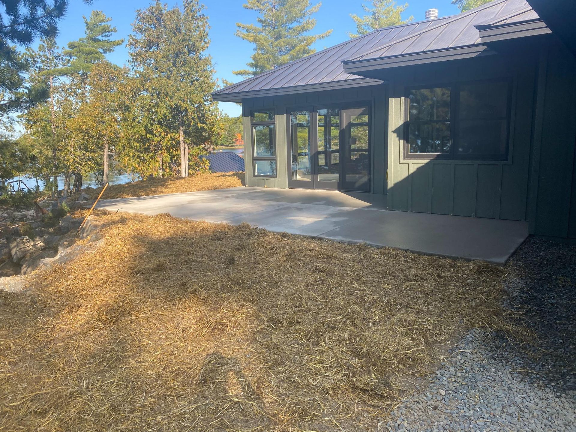 A house is sitting on top of a hill next to a lake.