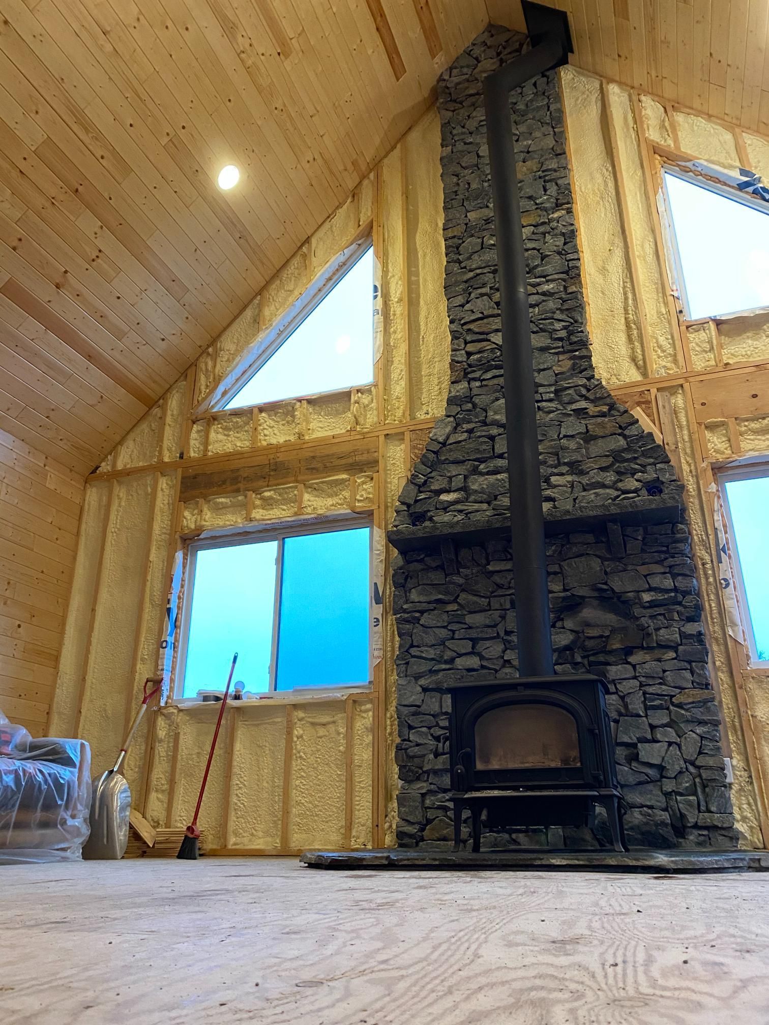 There is a large stone fireplace in the middle of the room.