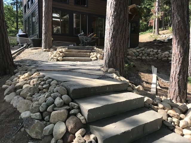 A stone walkway leading to a house in the woods