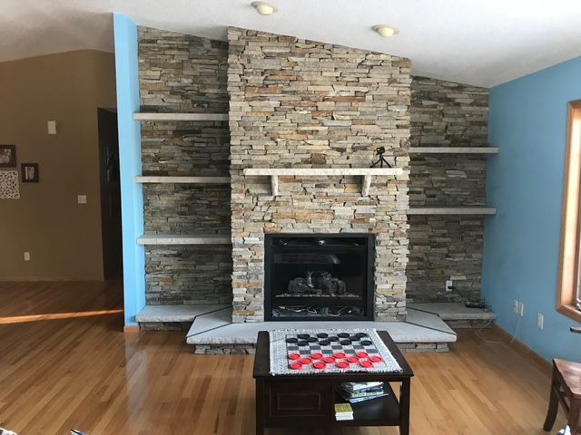 A living room with a stone fireplace and a coffee table