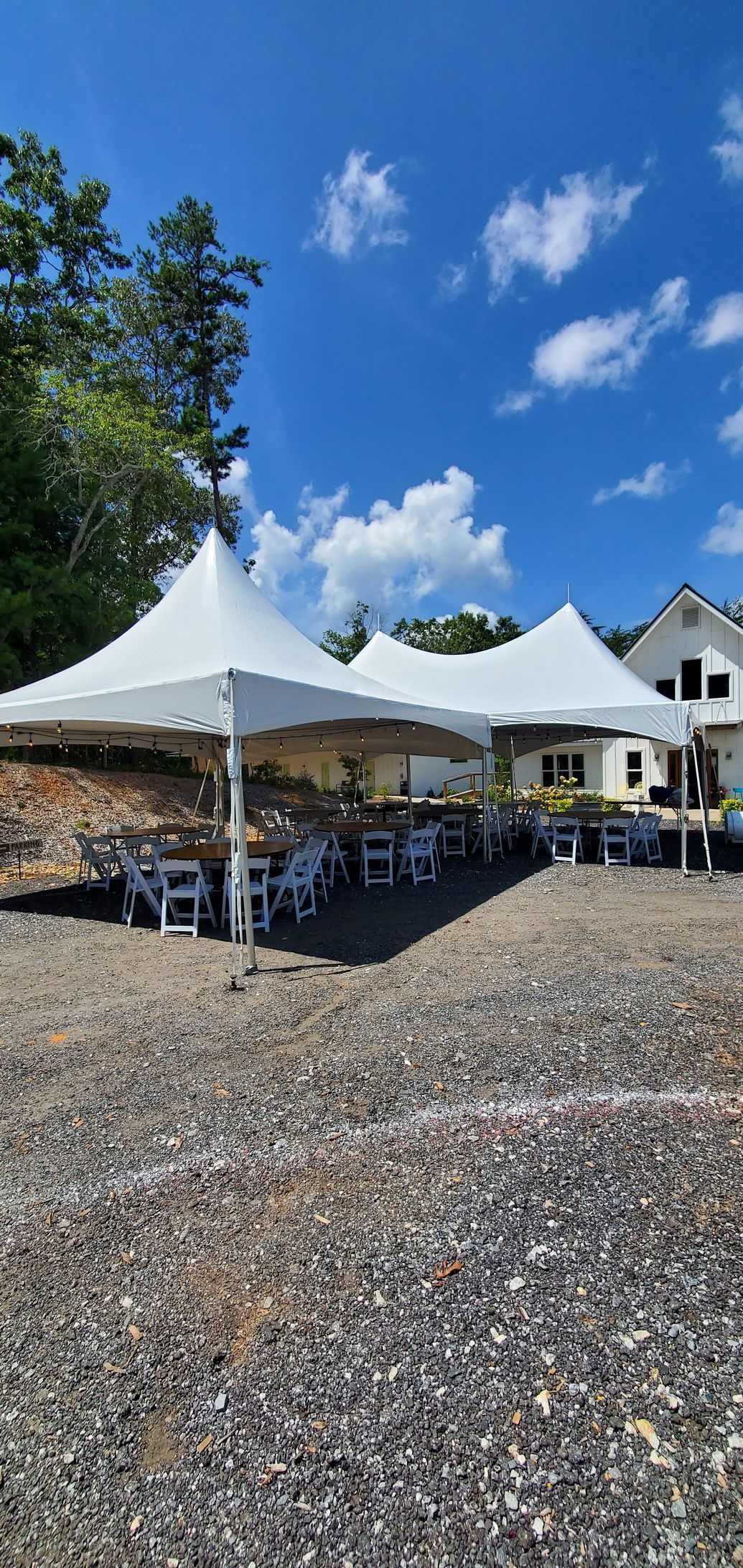 a group of tents are sitting on top of a dirt field in front of a house