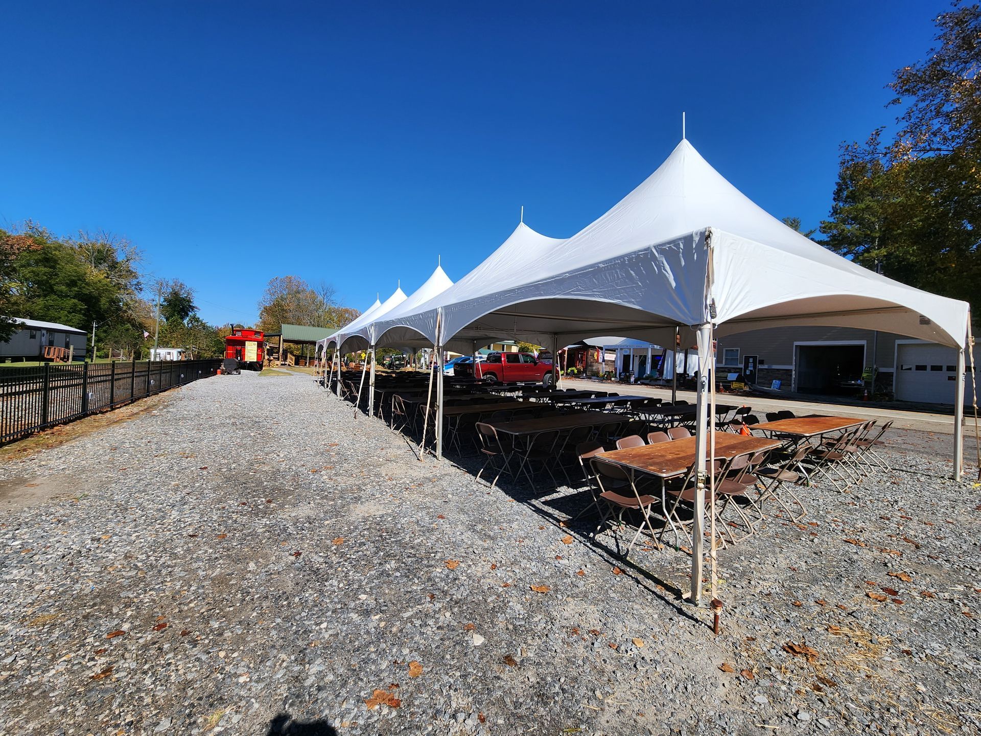 A row of white tents are sitting on top of a gravel road.