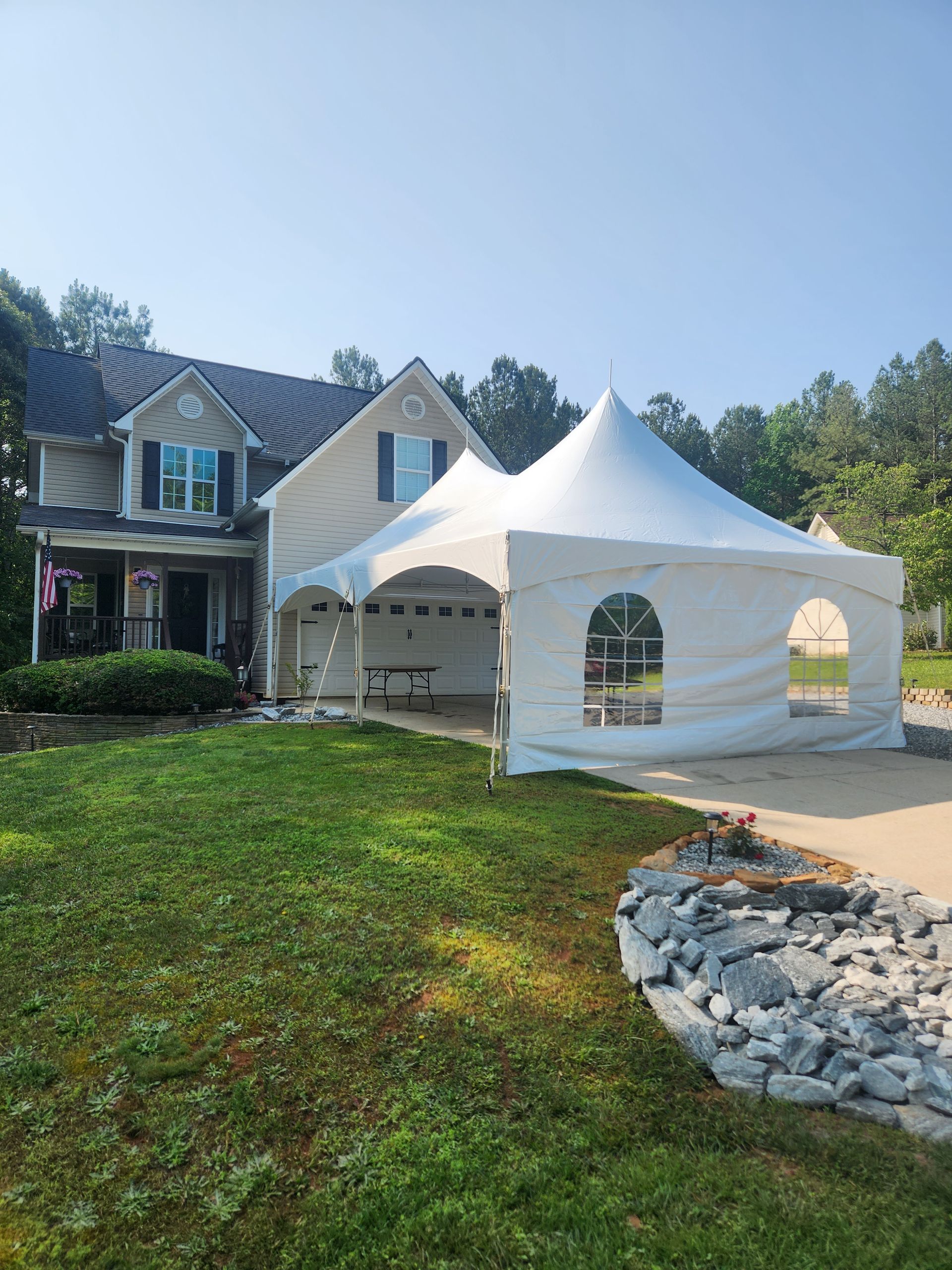 A white tent is sitting in front of a house.
