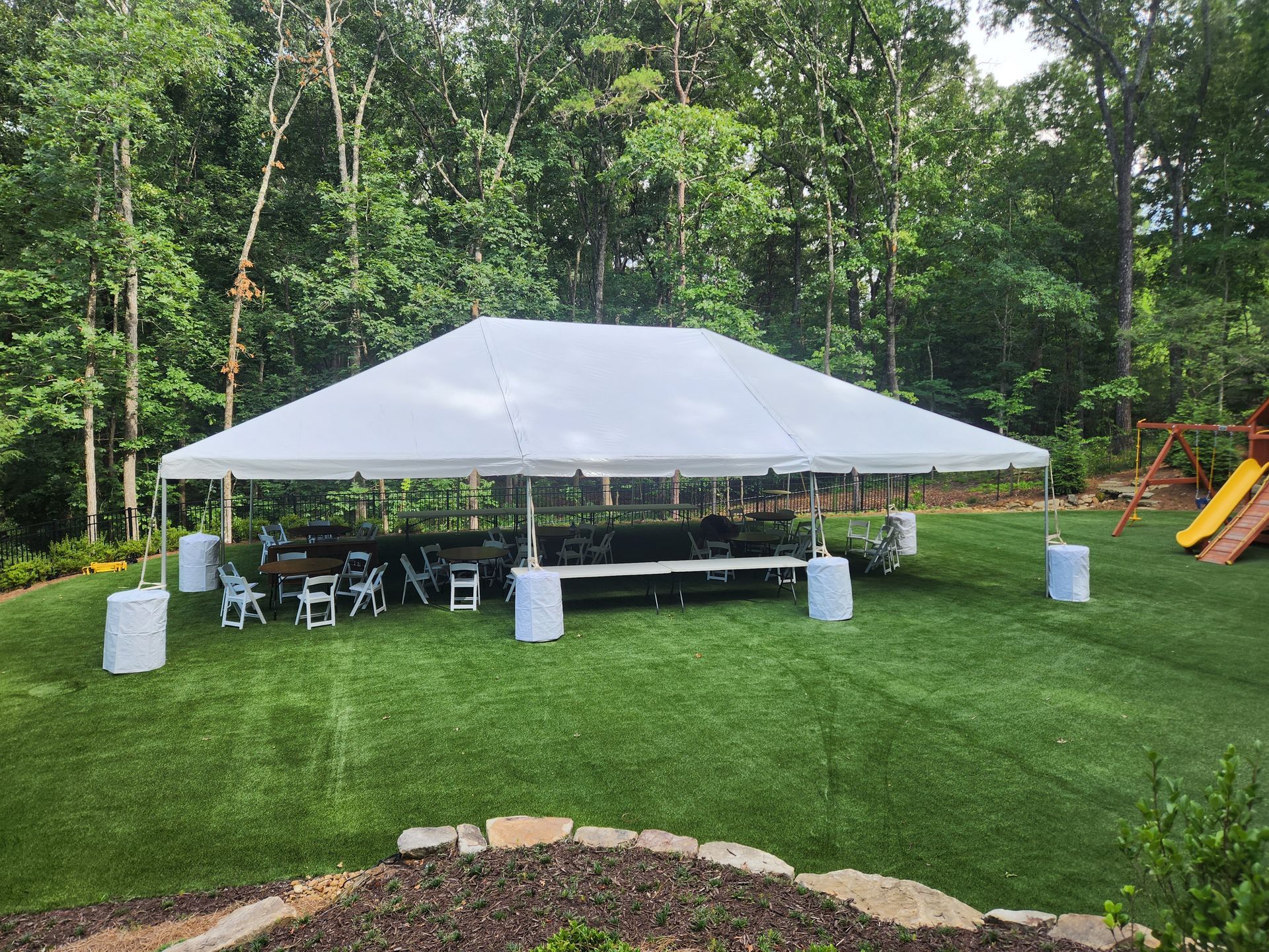 A large white tent is sitting in the middle of a lush green field.