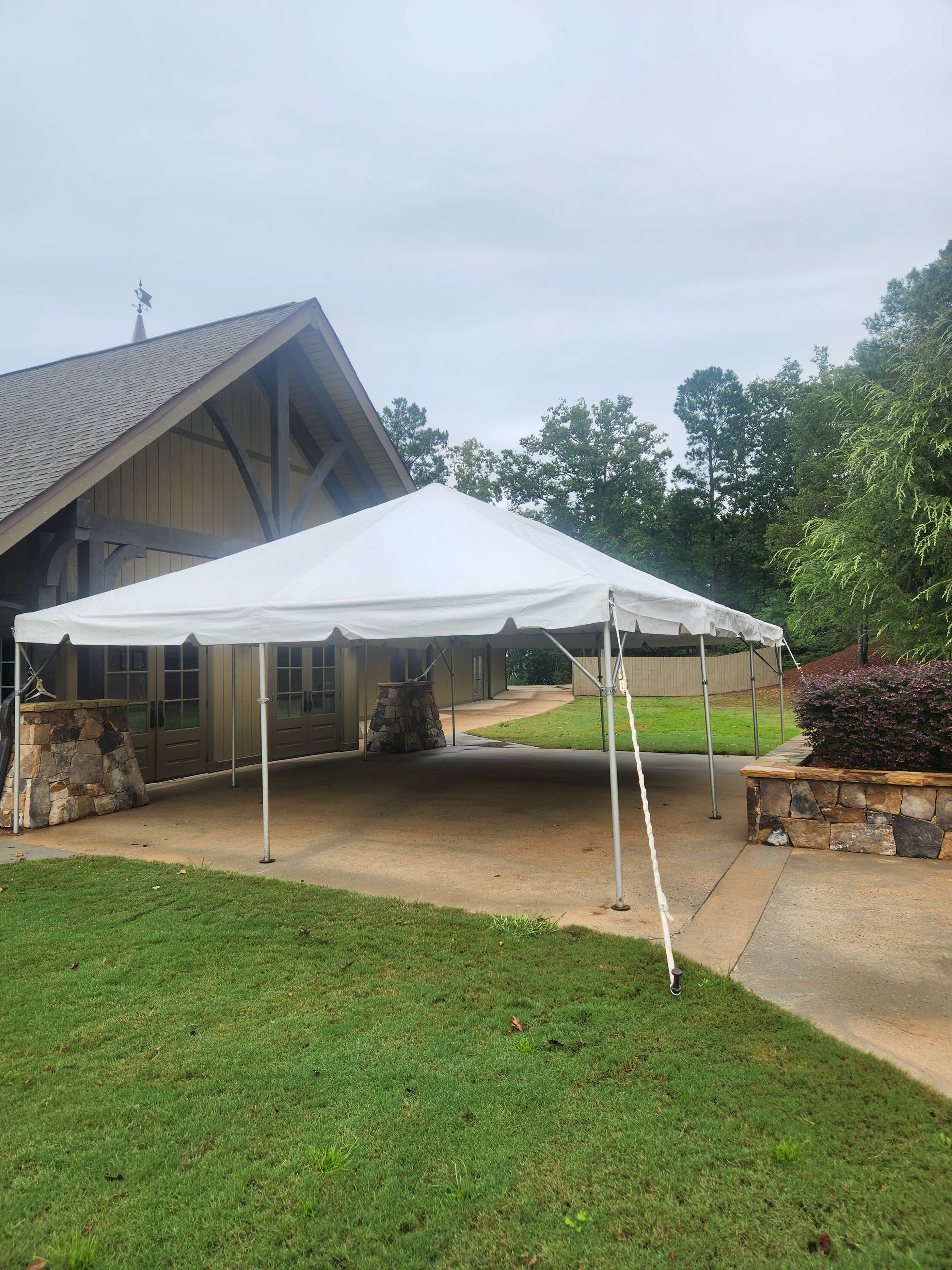 A large white tent is sitting in front of a house.