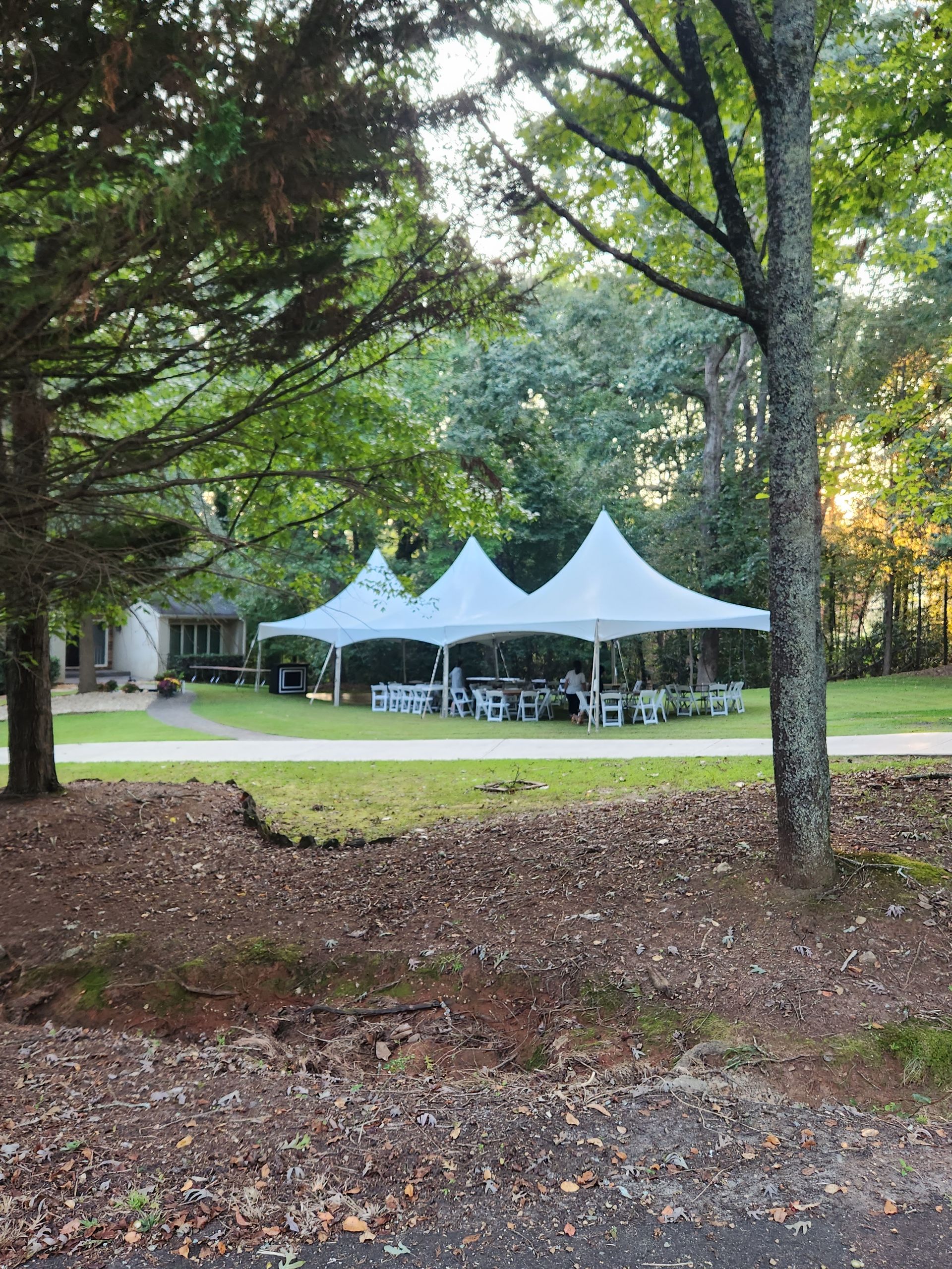 A couple of tents are sitting in the middle of a field surrounded by trees.