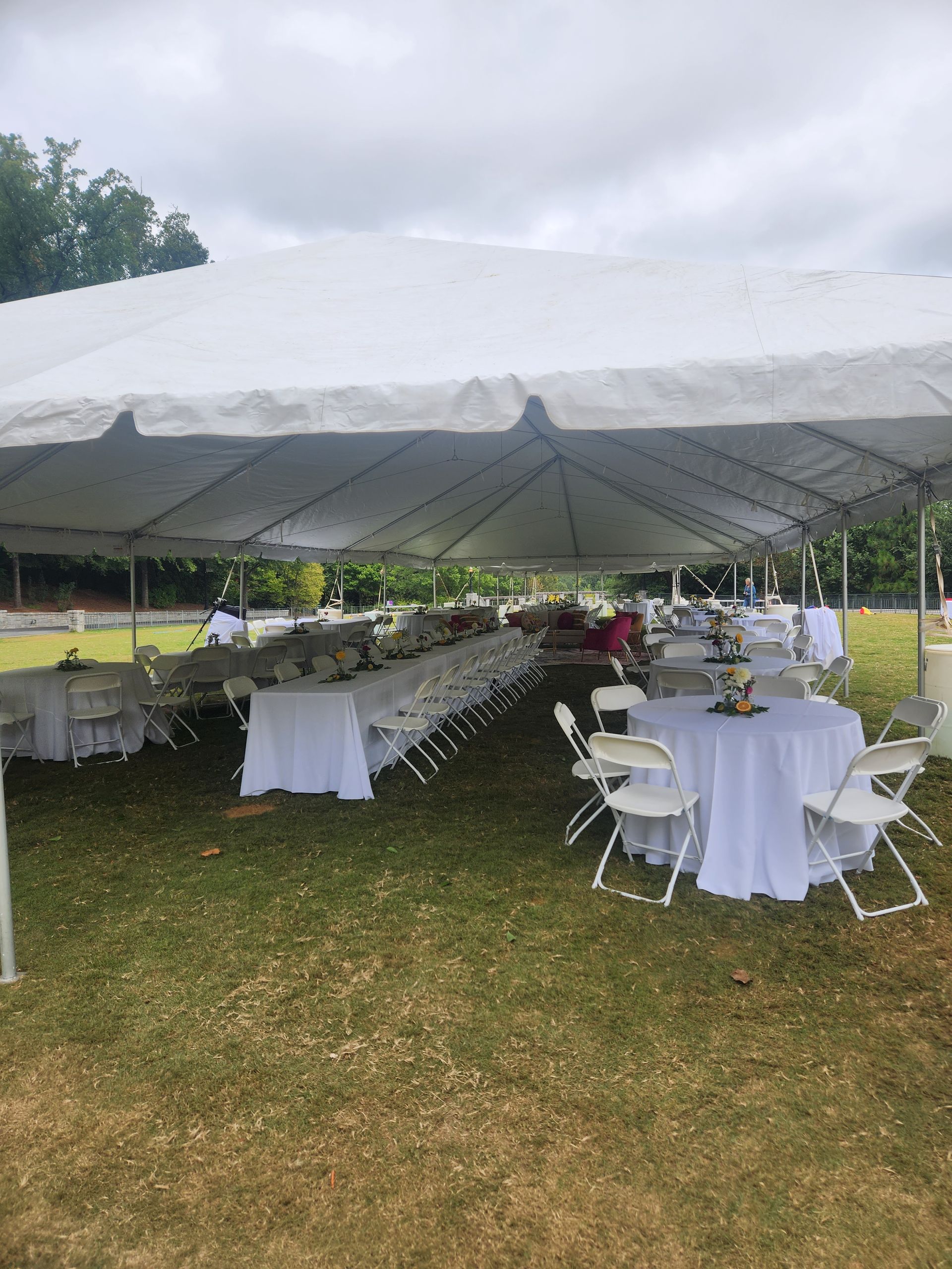 A large tent with tables and chairs underneath it in a field.