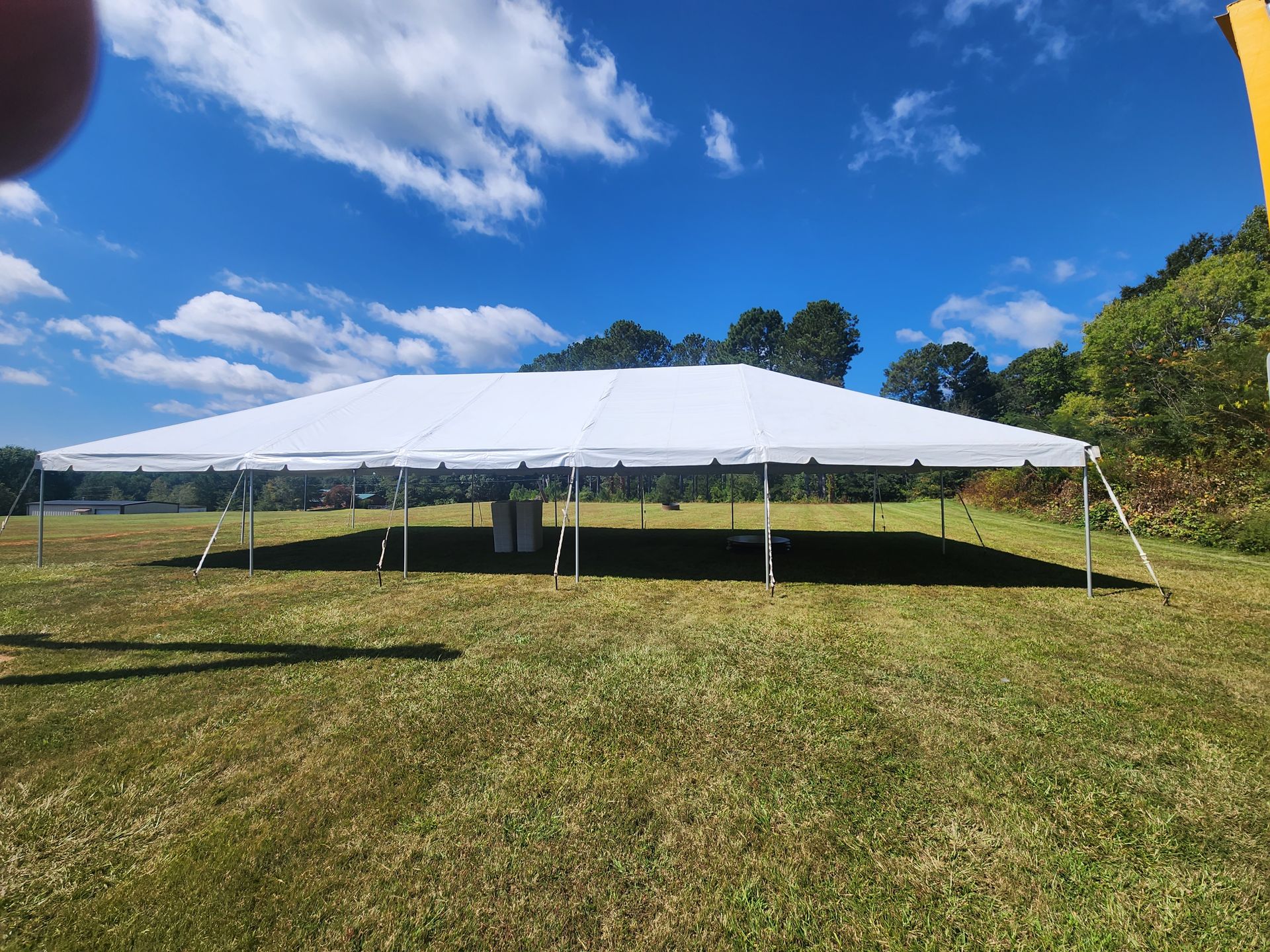 A large white tent is sitting in the middle of a grassy field.