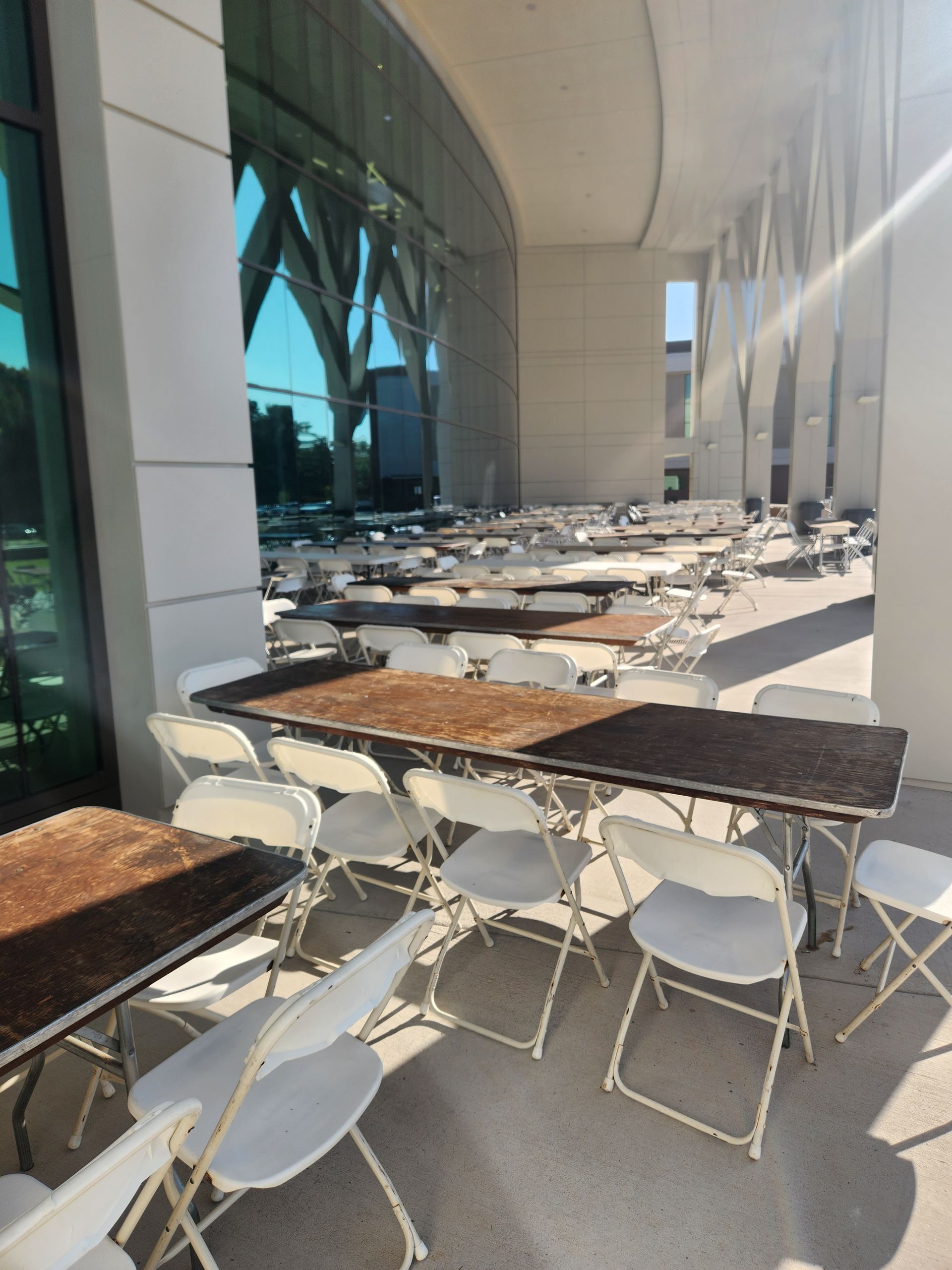 A row of folding chairs and tables outside of a building