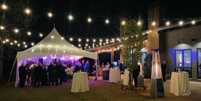 a group of people are standing under a tent at night