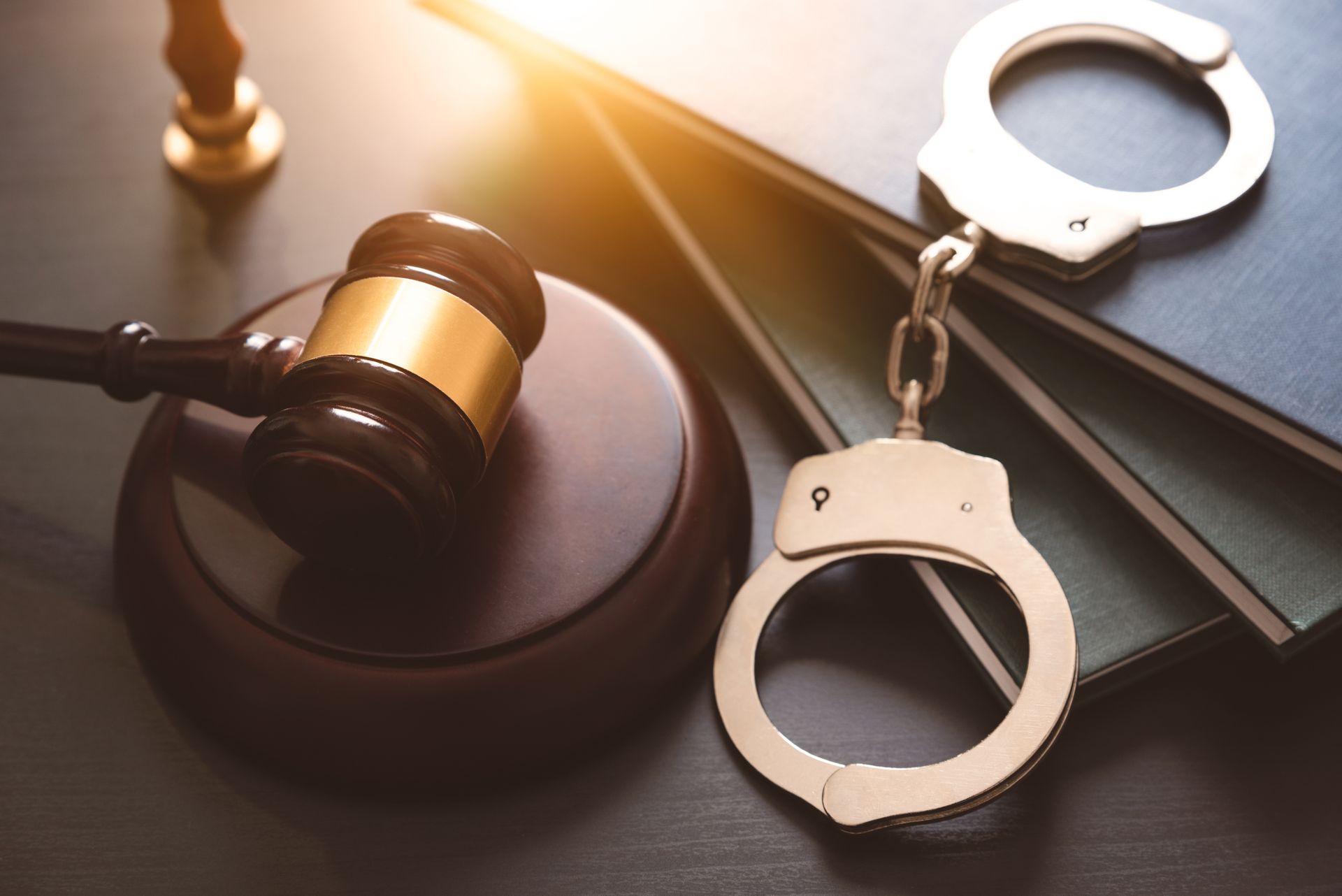 Judge’s gavel beside handcuffs and law book, symbolizing justice and criminal law. Judge’s gavel beside handcuffs and law book, symbolizing justice and criminal law.