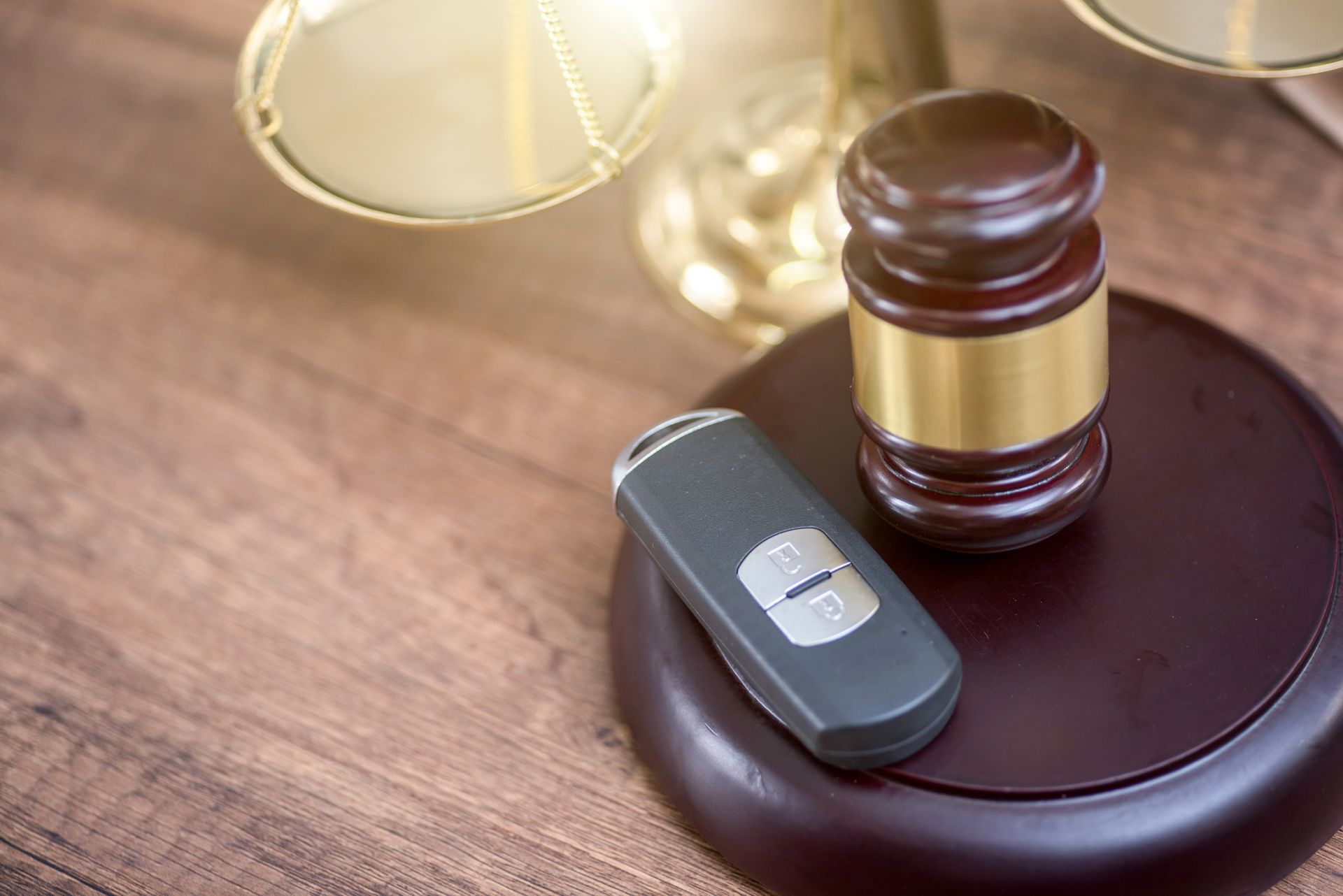 Gavel and car key on a wooden surface.