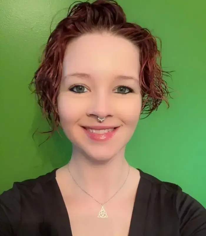 Woman with curly red hair smiles at the camera.