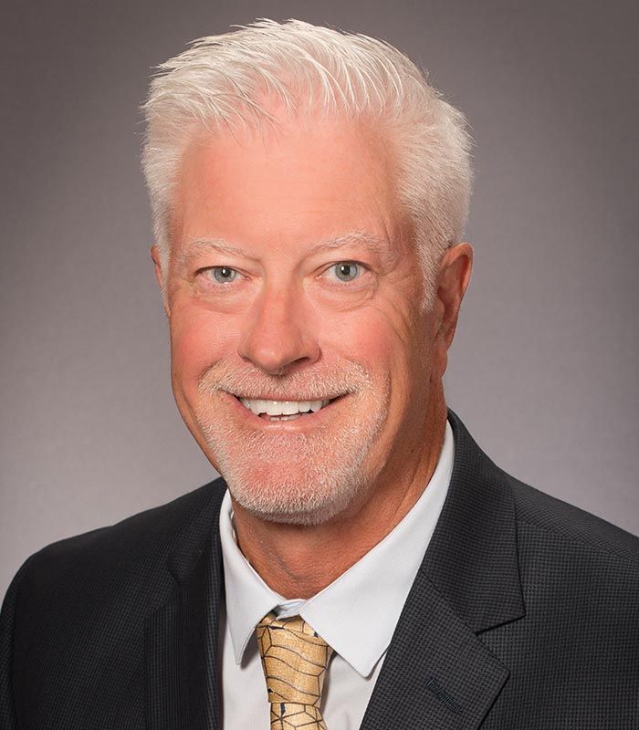 A man in a suit and tie is smiling for the camera