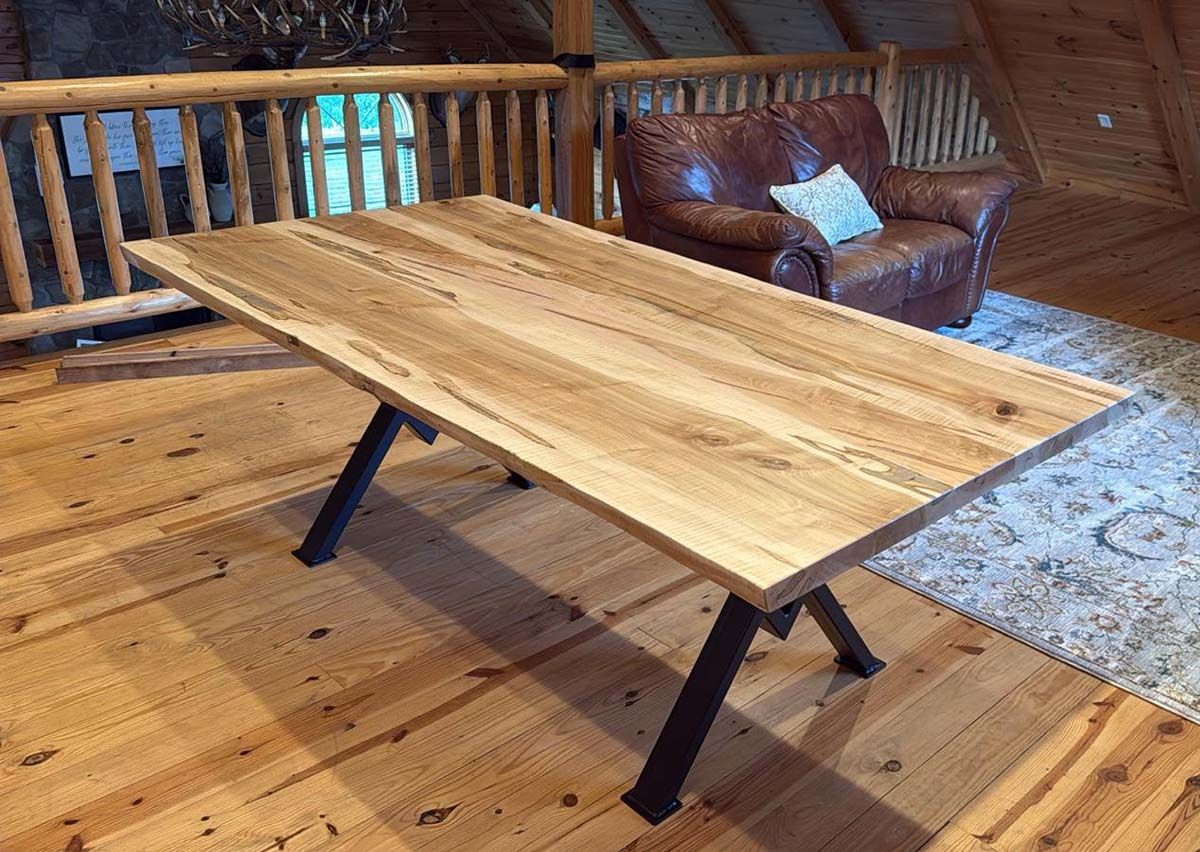 Wooden dining table with metal legs, brown leather armchair in a wooden-paneled room.