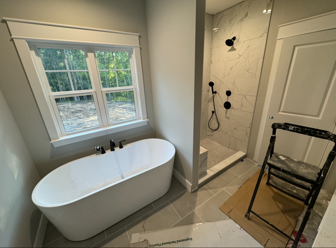 A bathroom with a tub , shower and window.