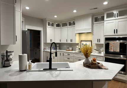 A kitchen with white cabinets , stainless steel appliances , a sink , and a large island.