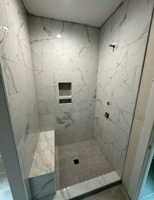 A bathroom with a walk in shower and a bench.