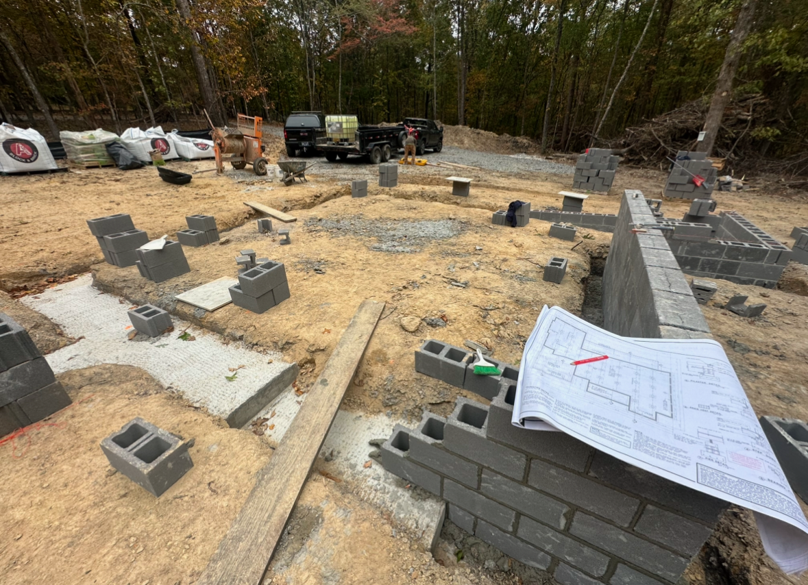 A construction site with bricks and a blueprint on the ground.