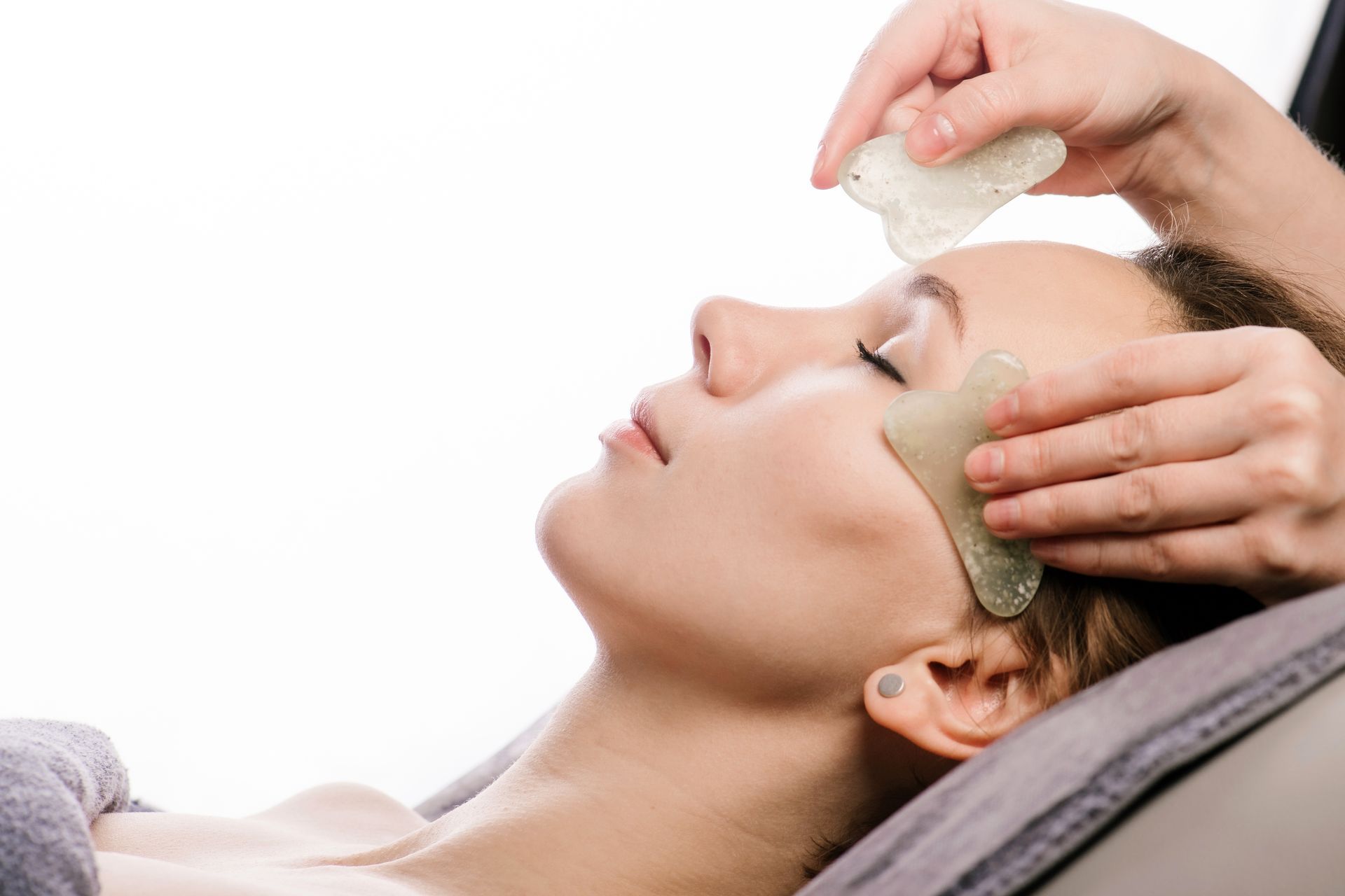 a woman is getting a gua sha treatment on her face .