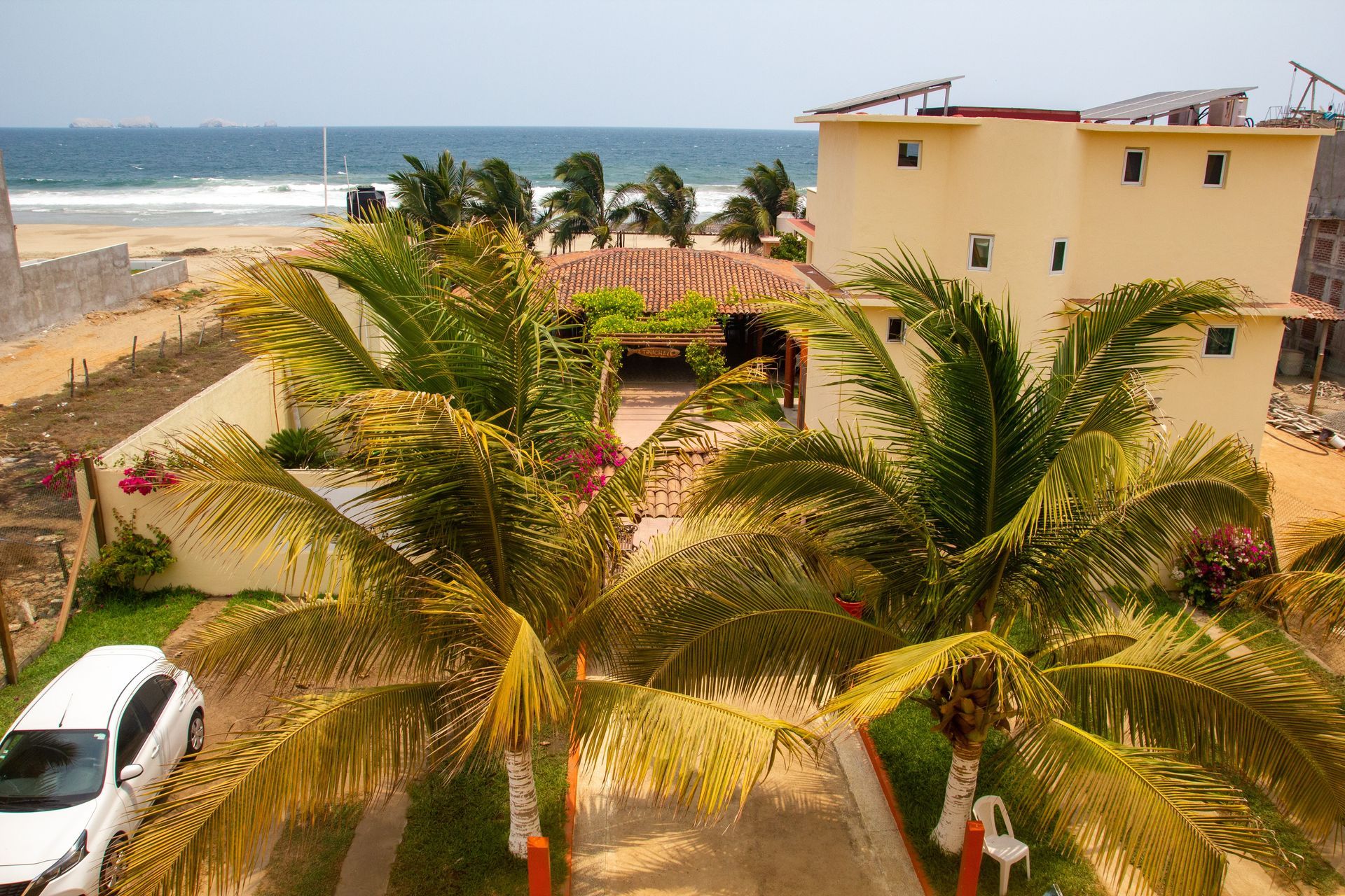 Un coche blanco está aparcado delante de un edificio con palmeras.