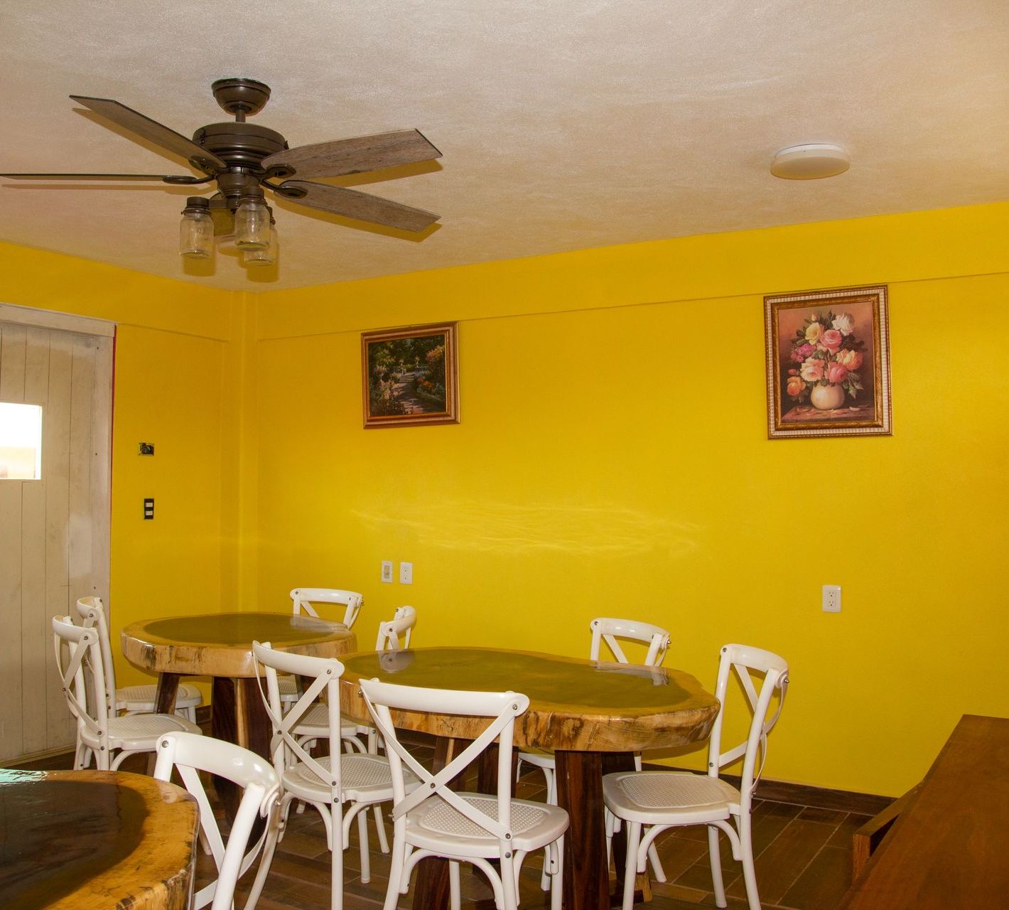 A dining room with yellow walls and a ceiling fan